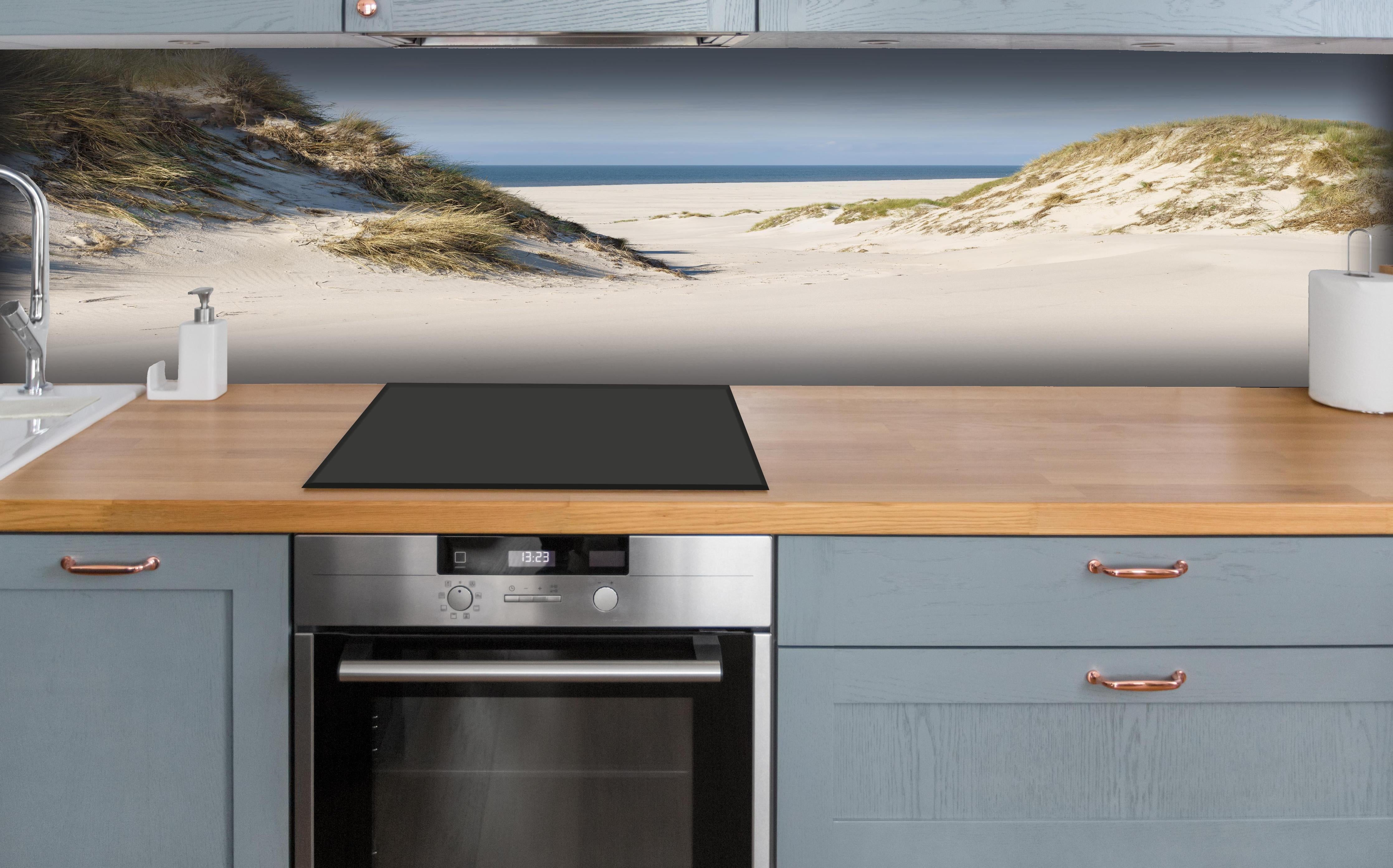 Küche - Traumhafte Sanddüne mit Blick auf das ruhige blaue Meer hinter weißen Hochglanz-Küchenregalen und schwarzem Wasserhahn