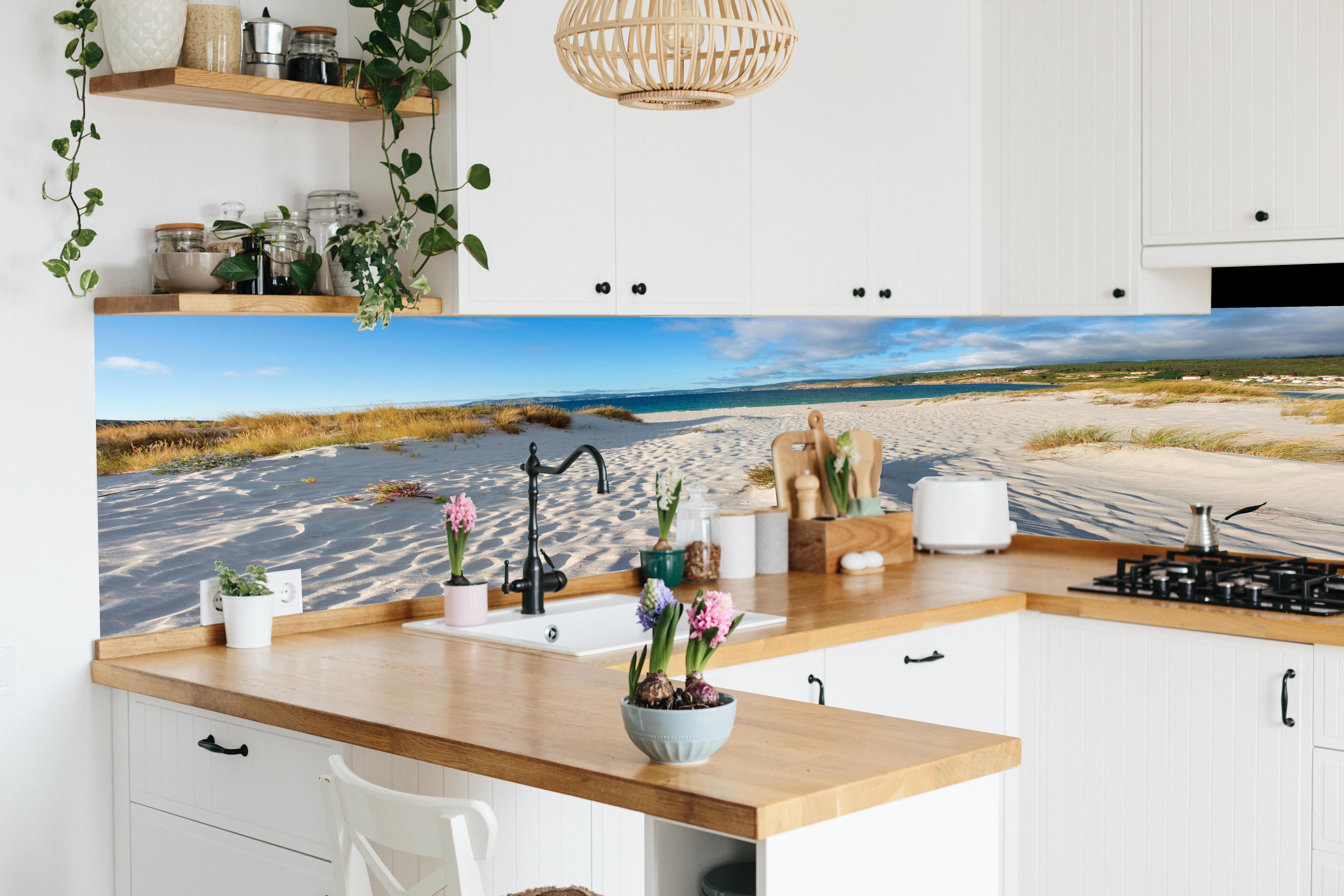 Küche - Traumhafte weiße Sanddünen mit sanftem Blau des Meeres und Himmel hinter weißen Hochglanz-Küchenregalen und schwarzem Wasserhahn