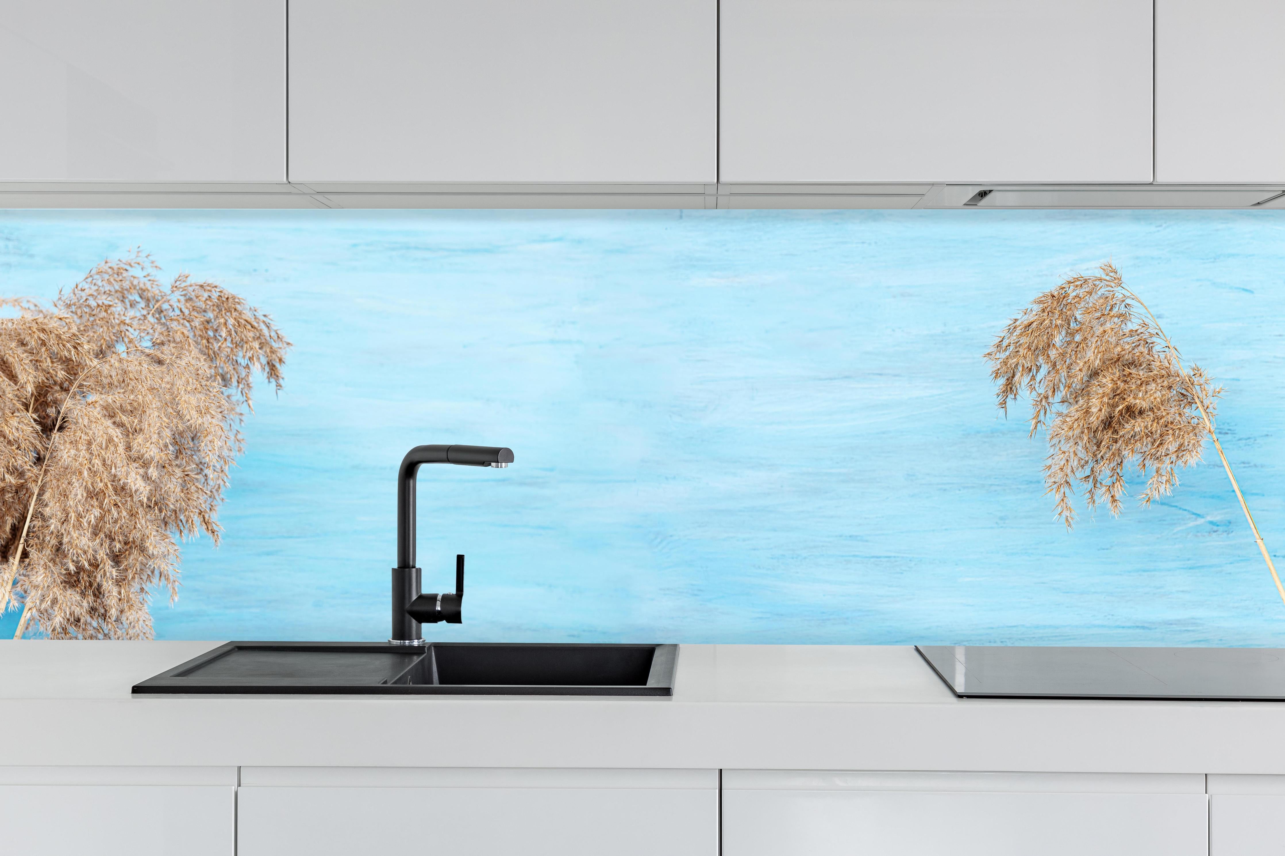 Küche - Trockene Pflanzen über dem Meer hinter weißen Hochglanz-Küchenregalen und schwarzem Wasserhahn