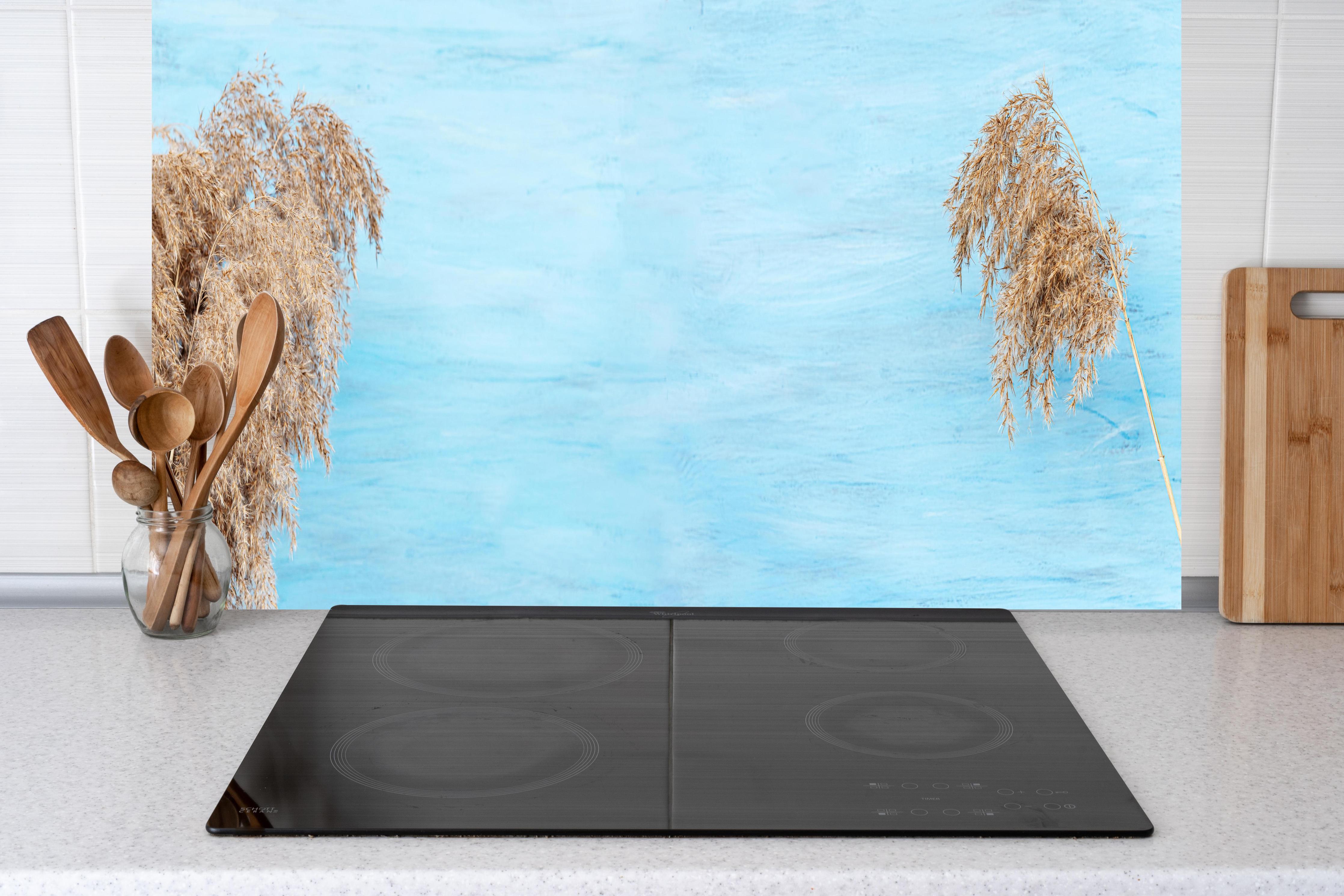 Küche - Trockene Pflanzen über dem Meer hinter weißen Hochglanz-Küchenregalen und schwarzem Wasserhahn