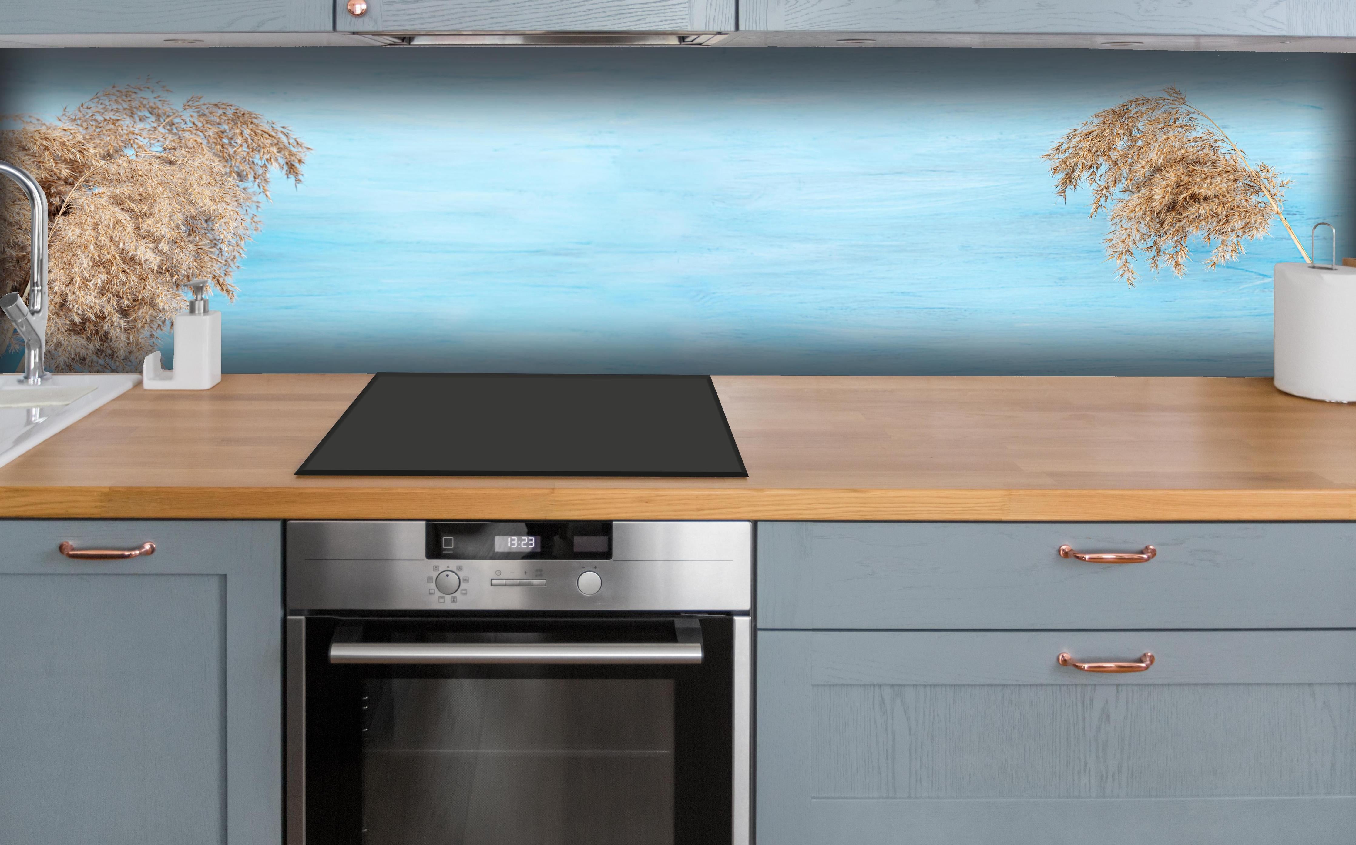 Küche - Trockene Pflanzen über dem Meer hinter weißen Hochglanz-Küchenregalen und schwarzem Wasserhahn