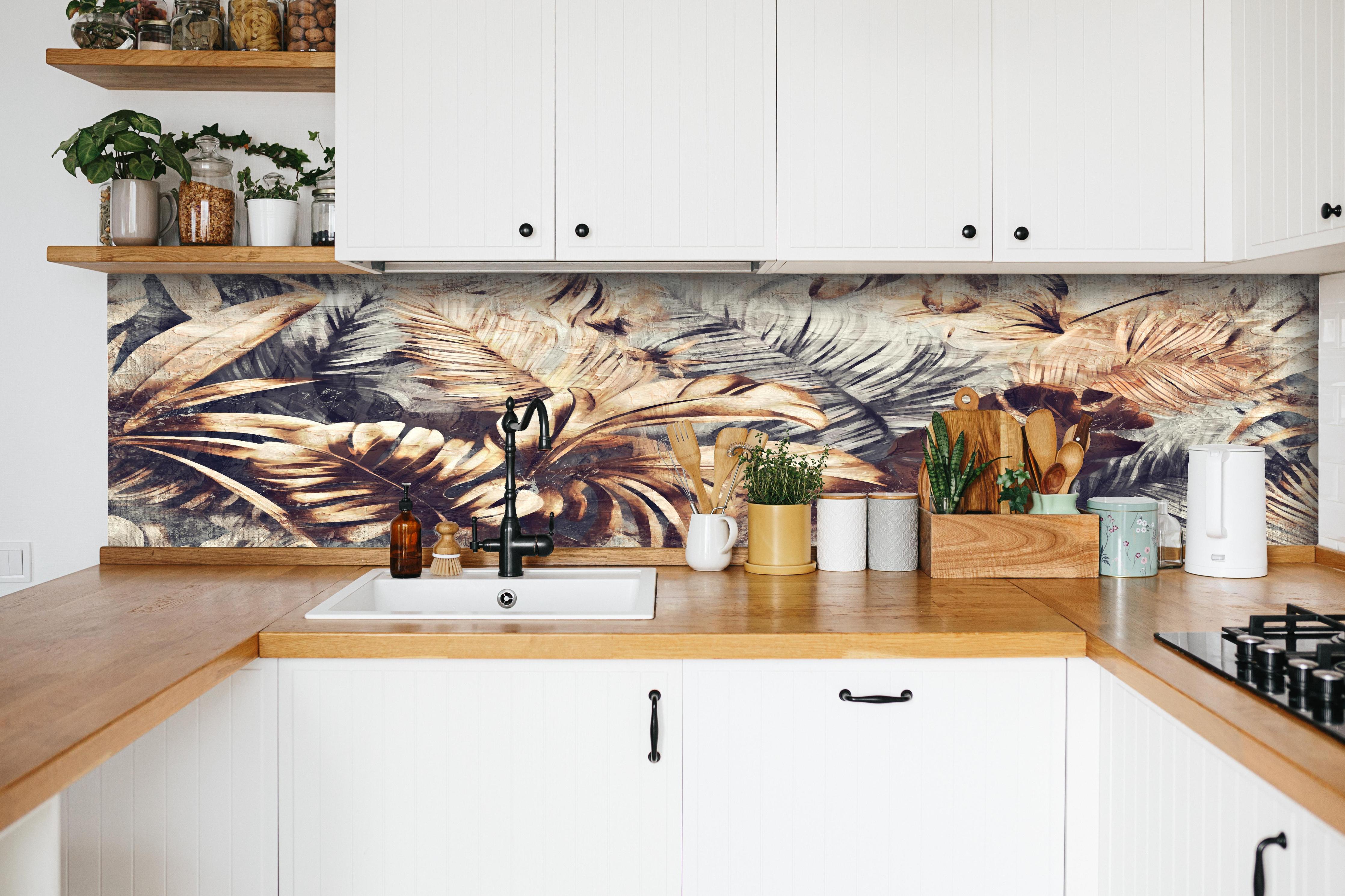 Küche - Tropische Palmenblätter in Gelb-Braun hinter weißen Hochglanz-Küchenregalen und schwarzem Wasserhahn