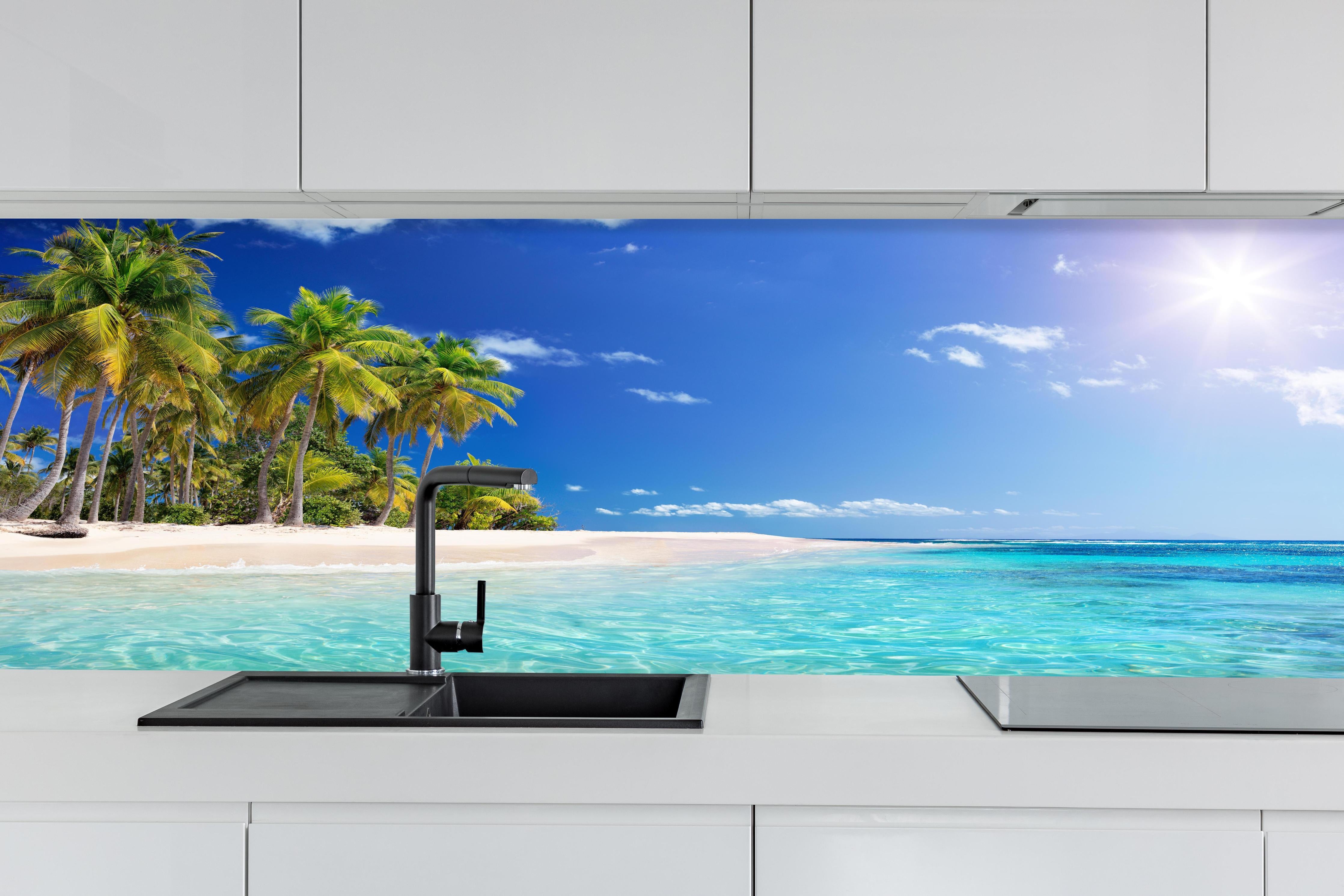 Küche - Tropisches Paradies mit strahlend blauem Himmel und palmenumsäumtem Strand hinter weißen Hochglanz-Küchenregalen und schwarzem Wasserhahn