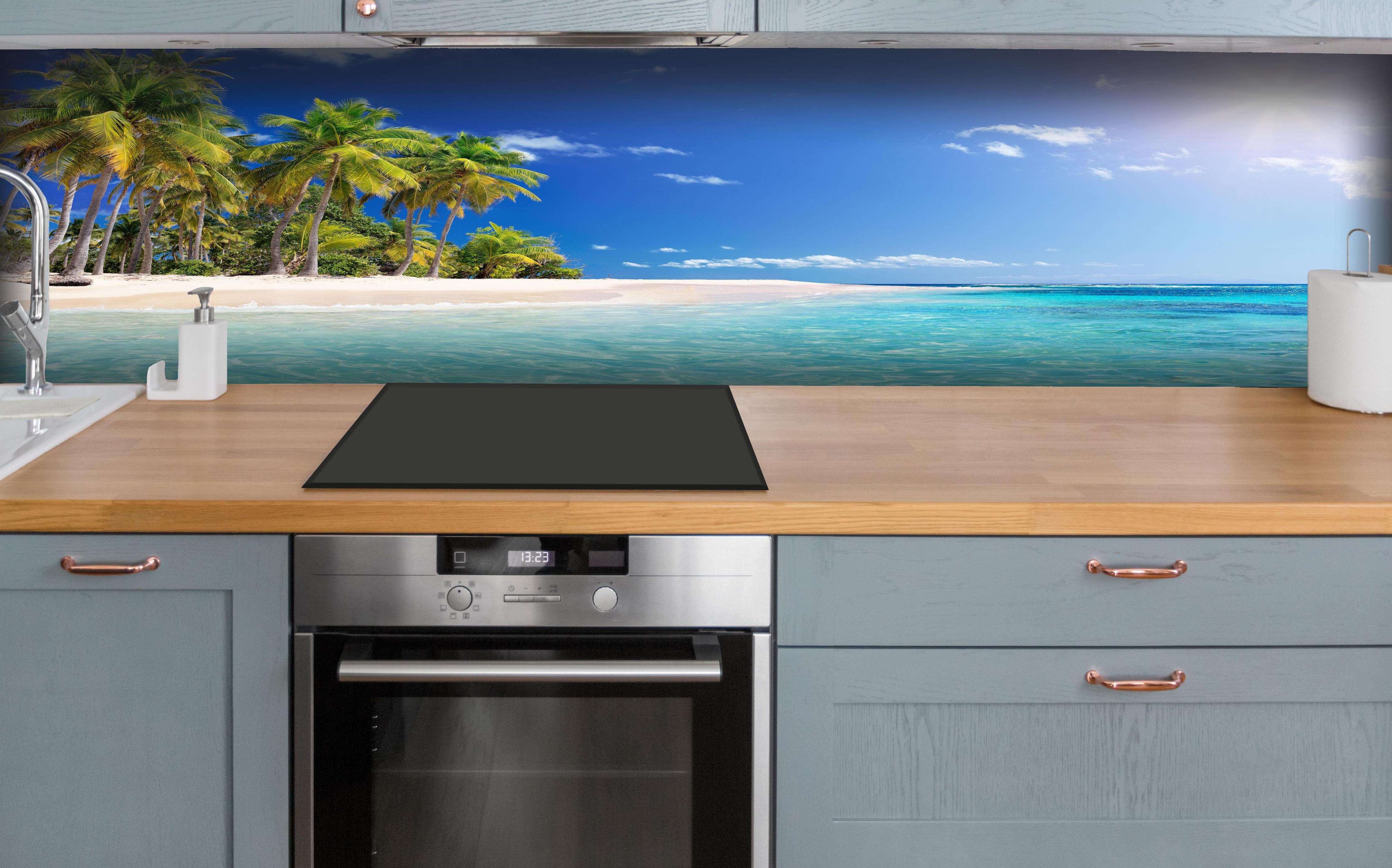 Küche - Tropisches Paradies mit strahlend blauem Himmel und palmenumsäumtem Strand hinter weißen Hochglanz-Küchenregalen und schwarzem Wasserhahn
