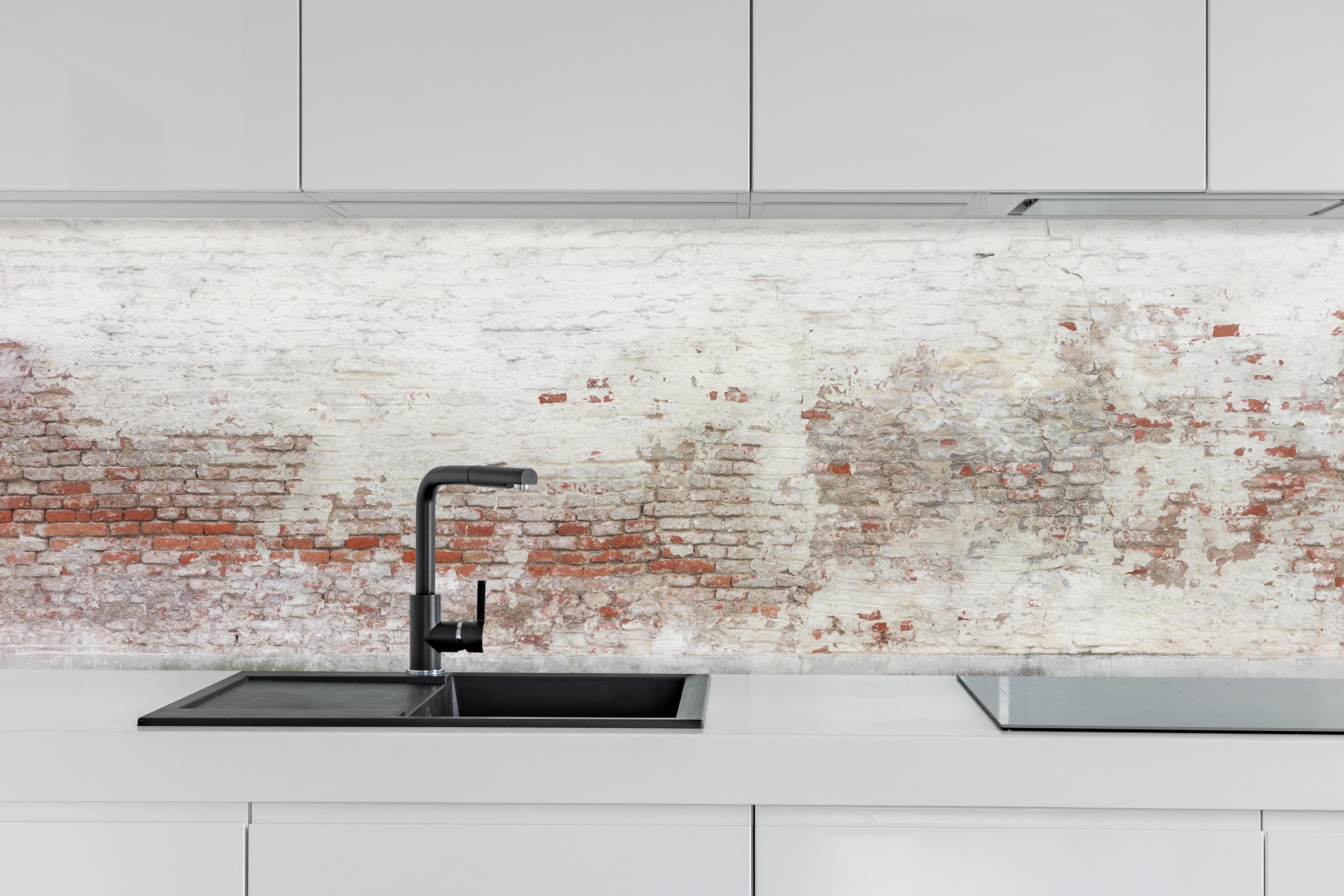 Küche - Veraltete Hauswand hinter weißen Hochglanz-Küchenregalen und schwarzem Wasserhahn