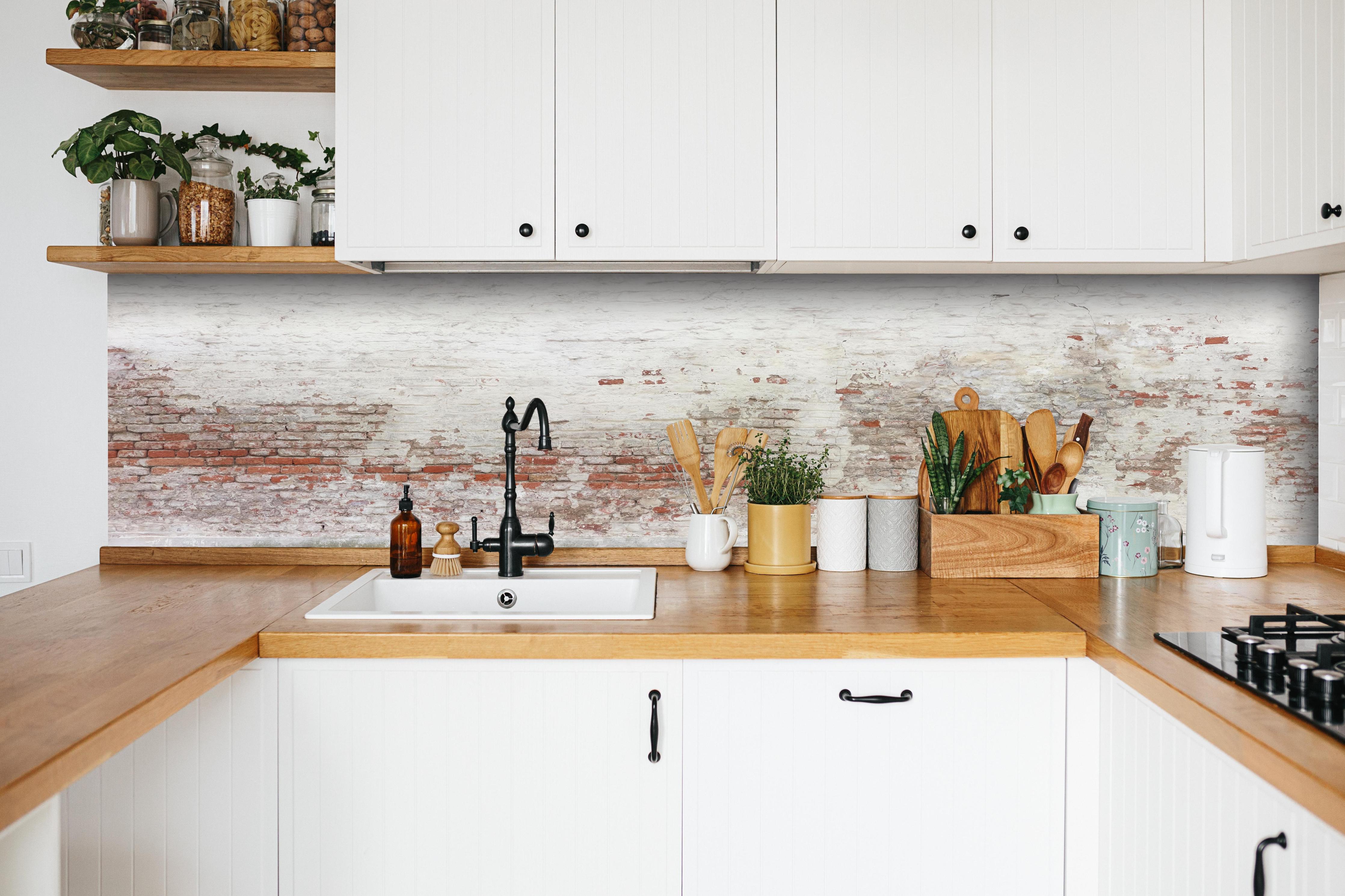 Küche - Veraltete Hauswand hinter weißen Hochglanz-Küchenregalen und schwarzem Wasserhahn