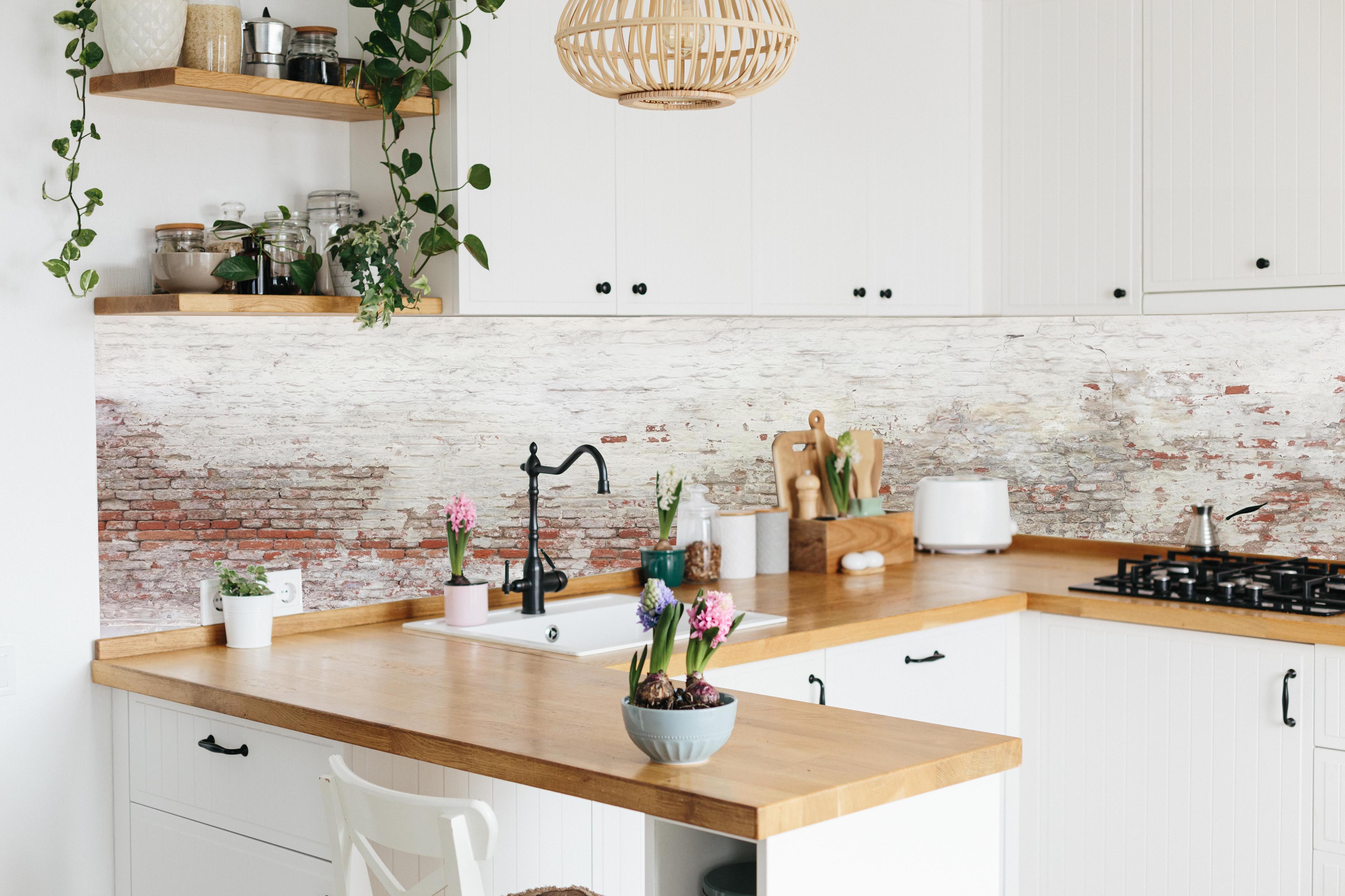 Küche - Veraltete Hauswand hinter weißen Hochglanz-Küchenregalen und schwarzem Wasserhahn