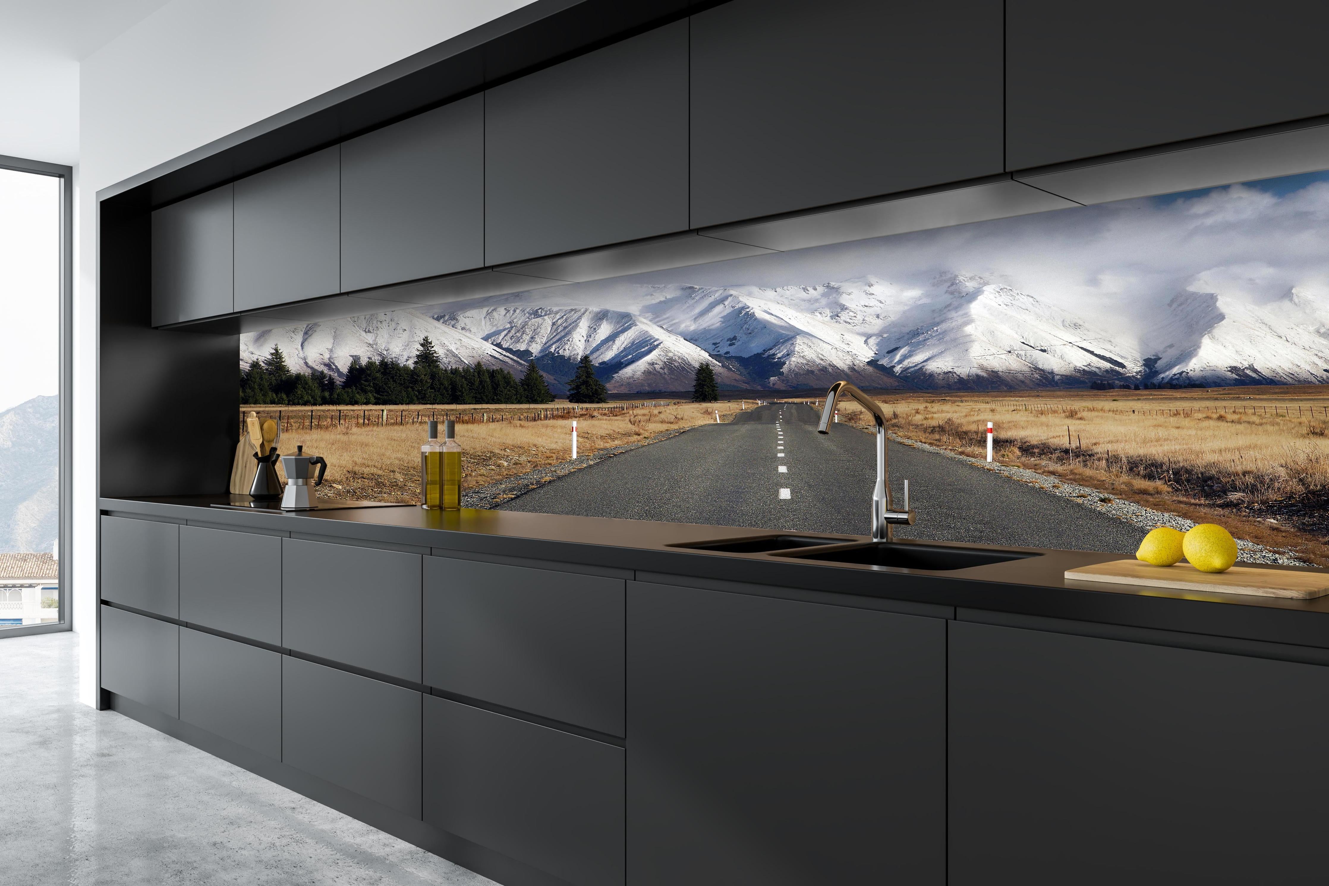 Küche - Verschneite Berglandschaft mit grauer Straße hinter weißen Hochglanz-Küchenregalen und schwarzem Wasserhahn