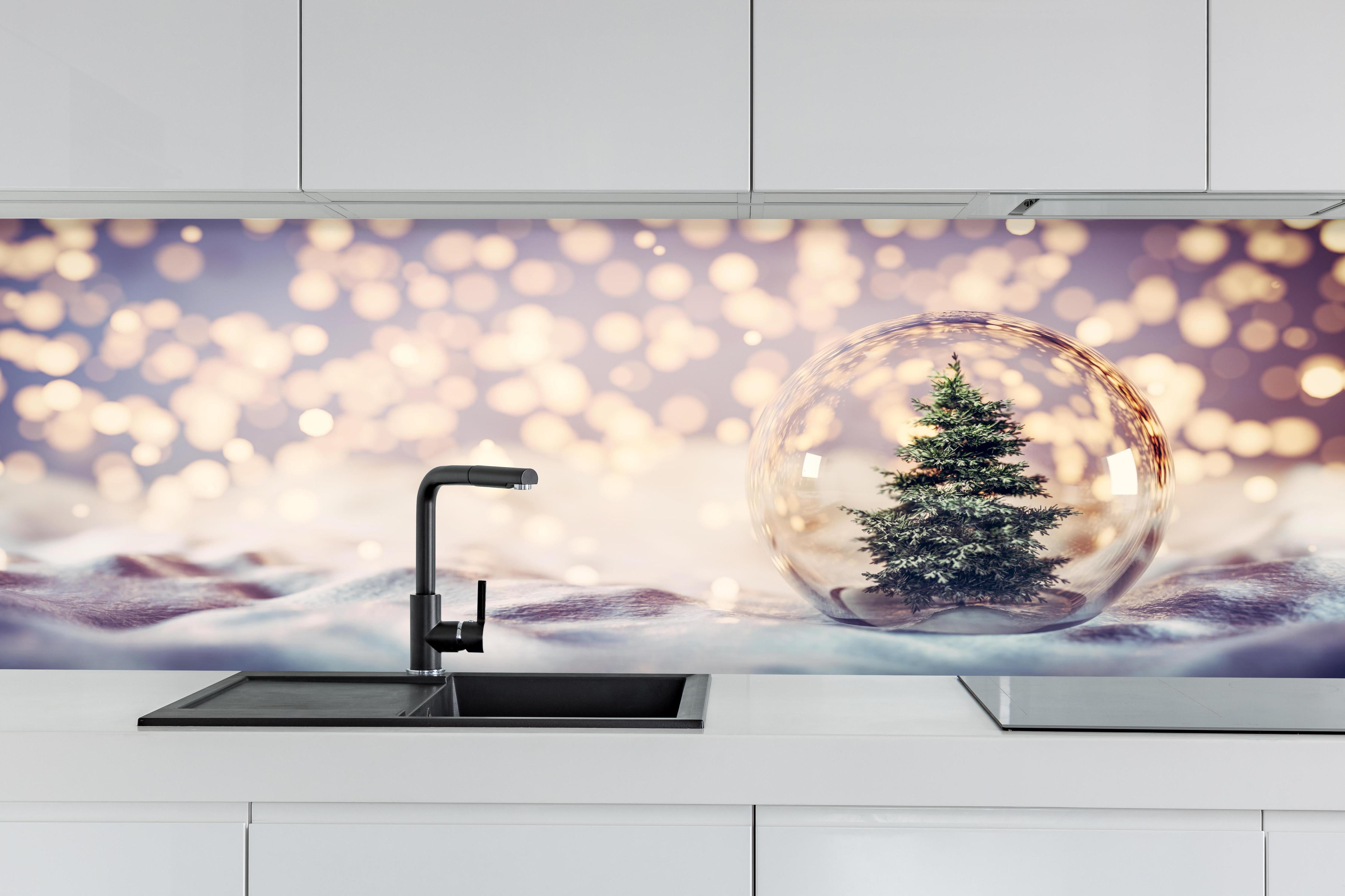 Küche - Weihnachtsbaum in einer Glaskugel hinter weißen Hochglanz-Küchenregalen und schwarzem Wasserhahn