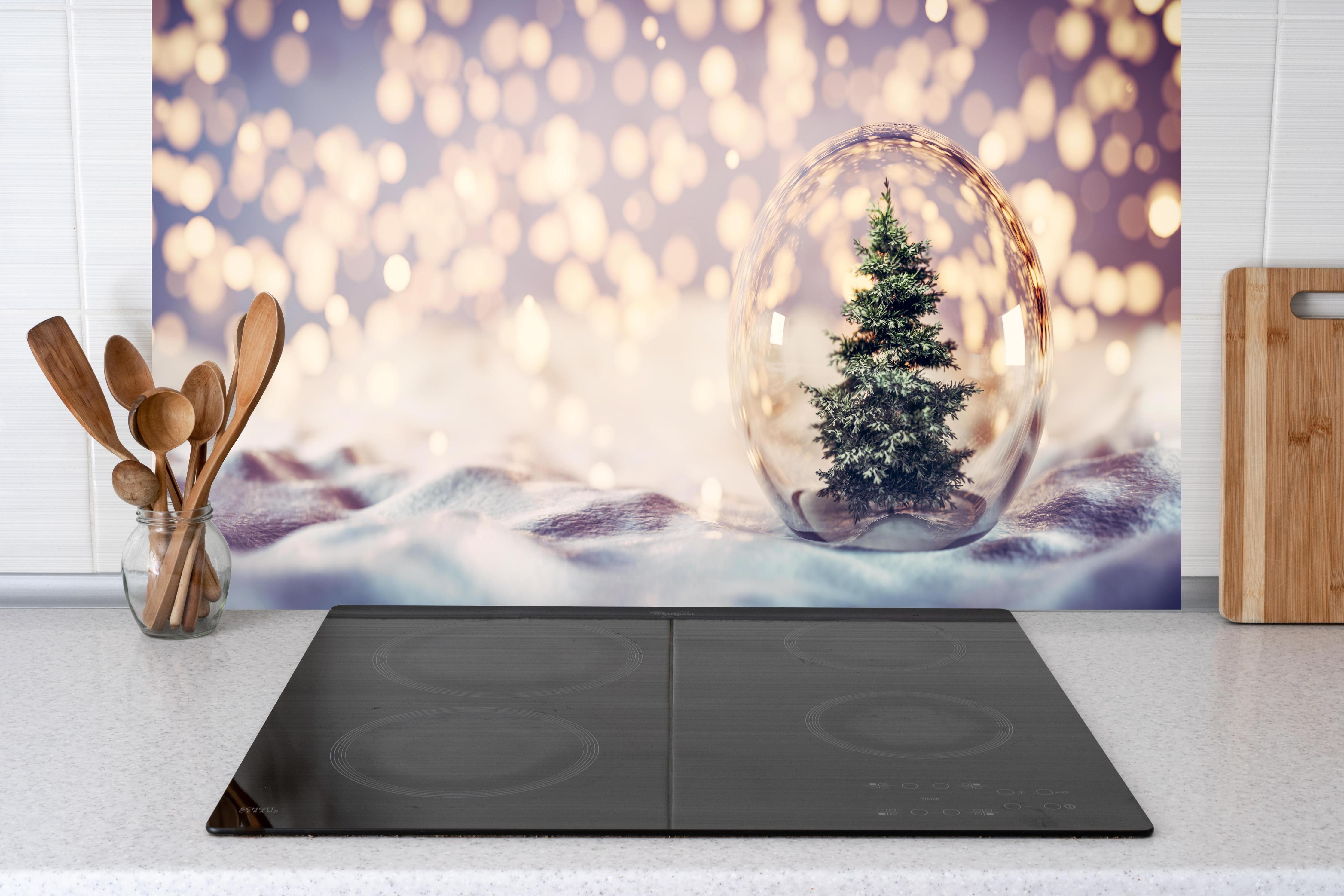 Küche - Weihnachtsbaum in einer Glaskugel hinter weißen Hochglanz-Küchenregalen und schwarzem Wasserhahn