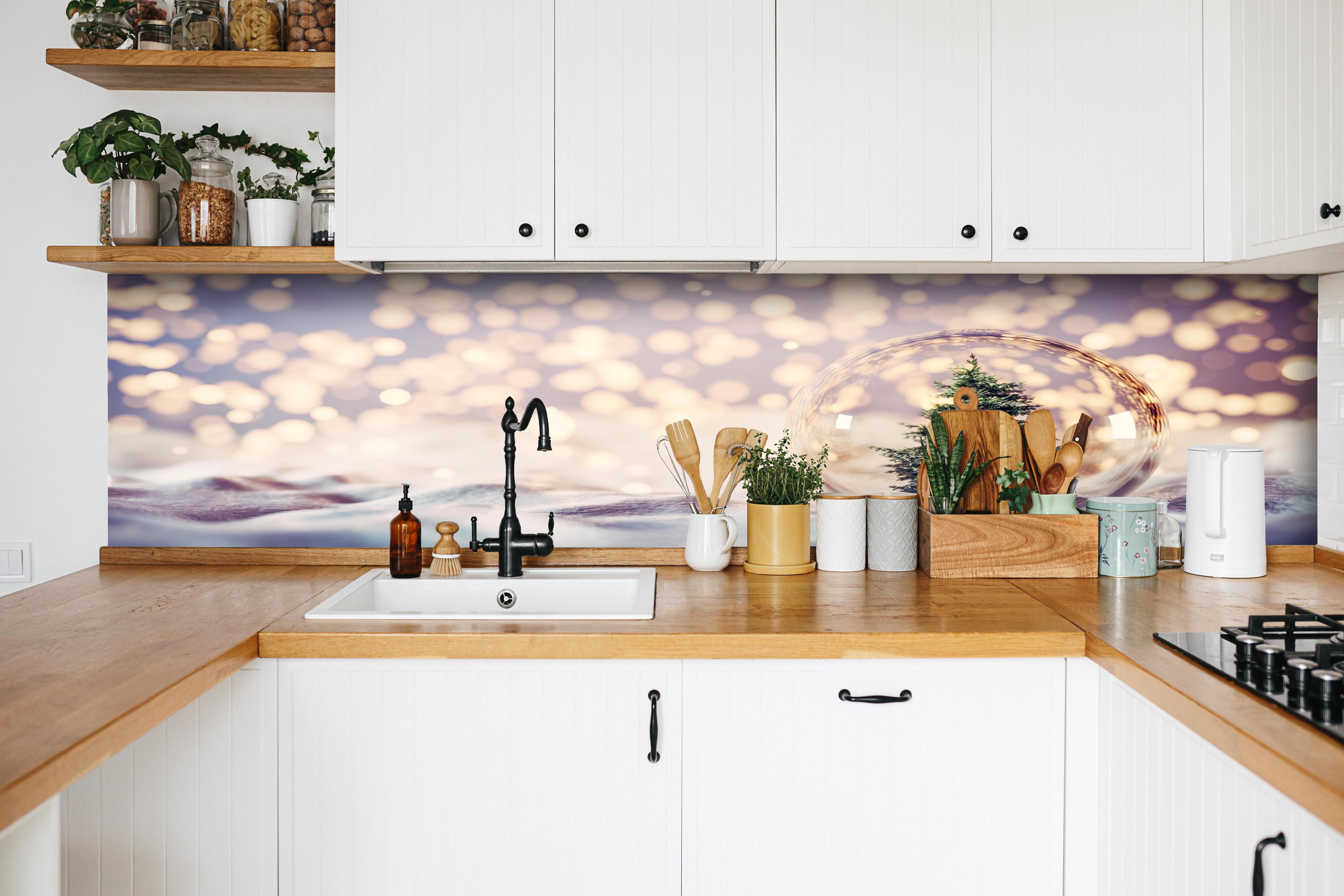 Küche - Weihnachtsbaum in einer Glaskugel hinter weißen Hochglanz-Küchenregalen und schwarzem Wasserhahn