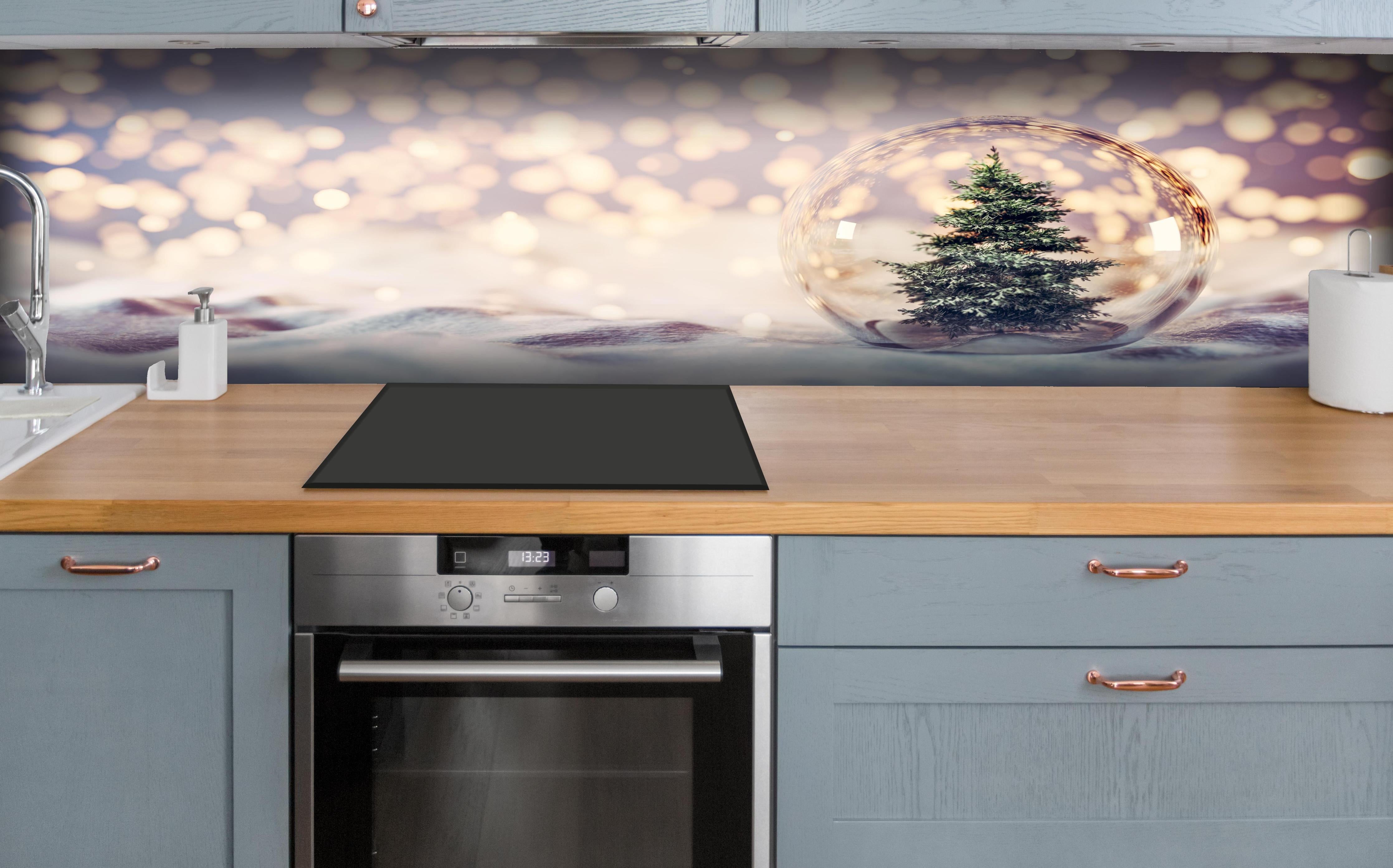 Küche - Weihnachtsbaum in einer Glaskugel hinter weißen Hochglanz-Küchenregalen und schwarzem Wasserhahn