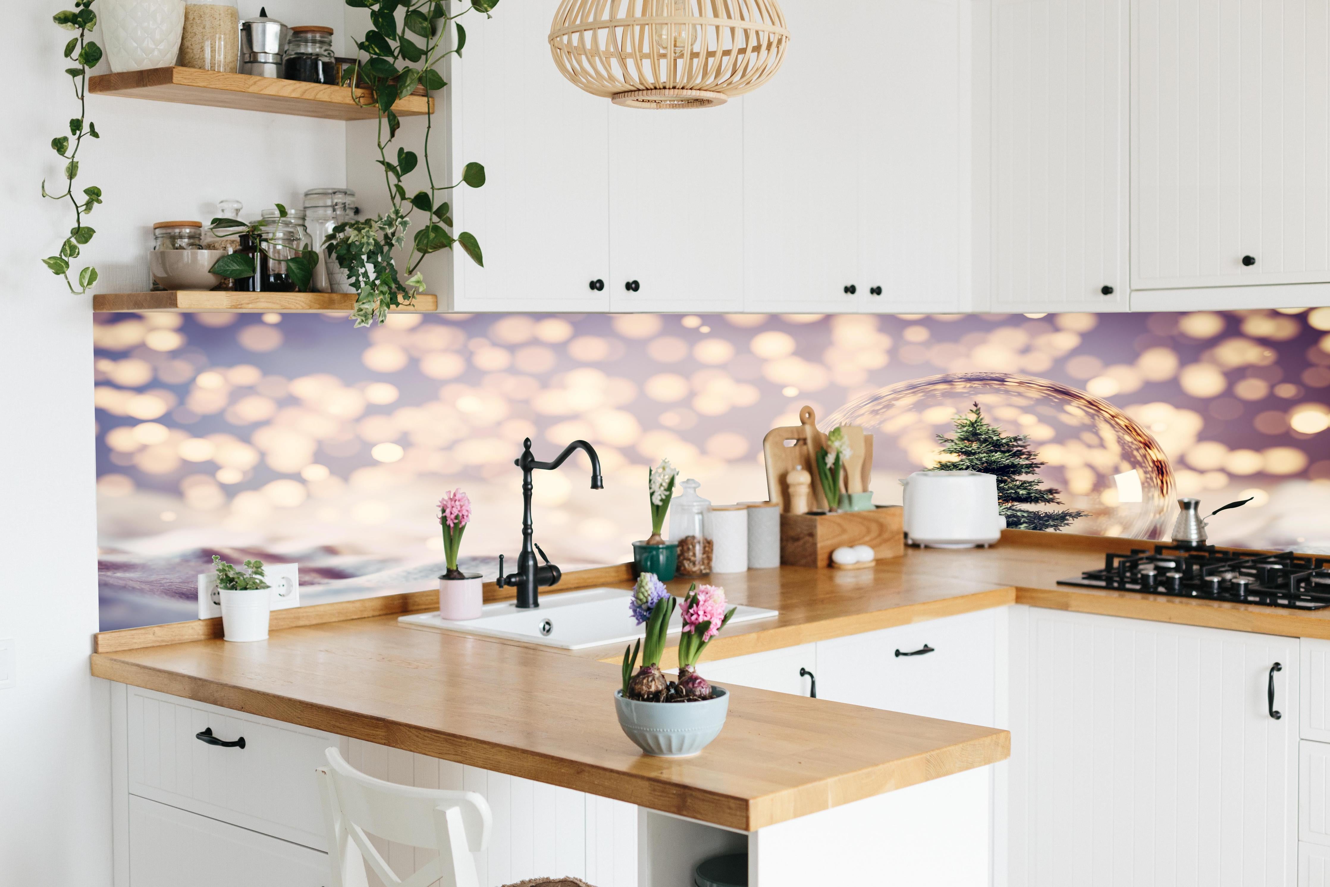 Küche - Weihnachtsbaum in einer Glaskugel hinter weißen Hochglanz-Küchenregalen und schwarzem Wasserhahn