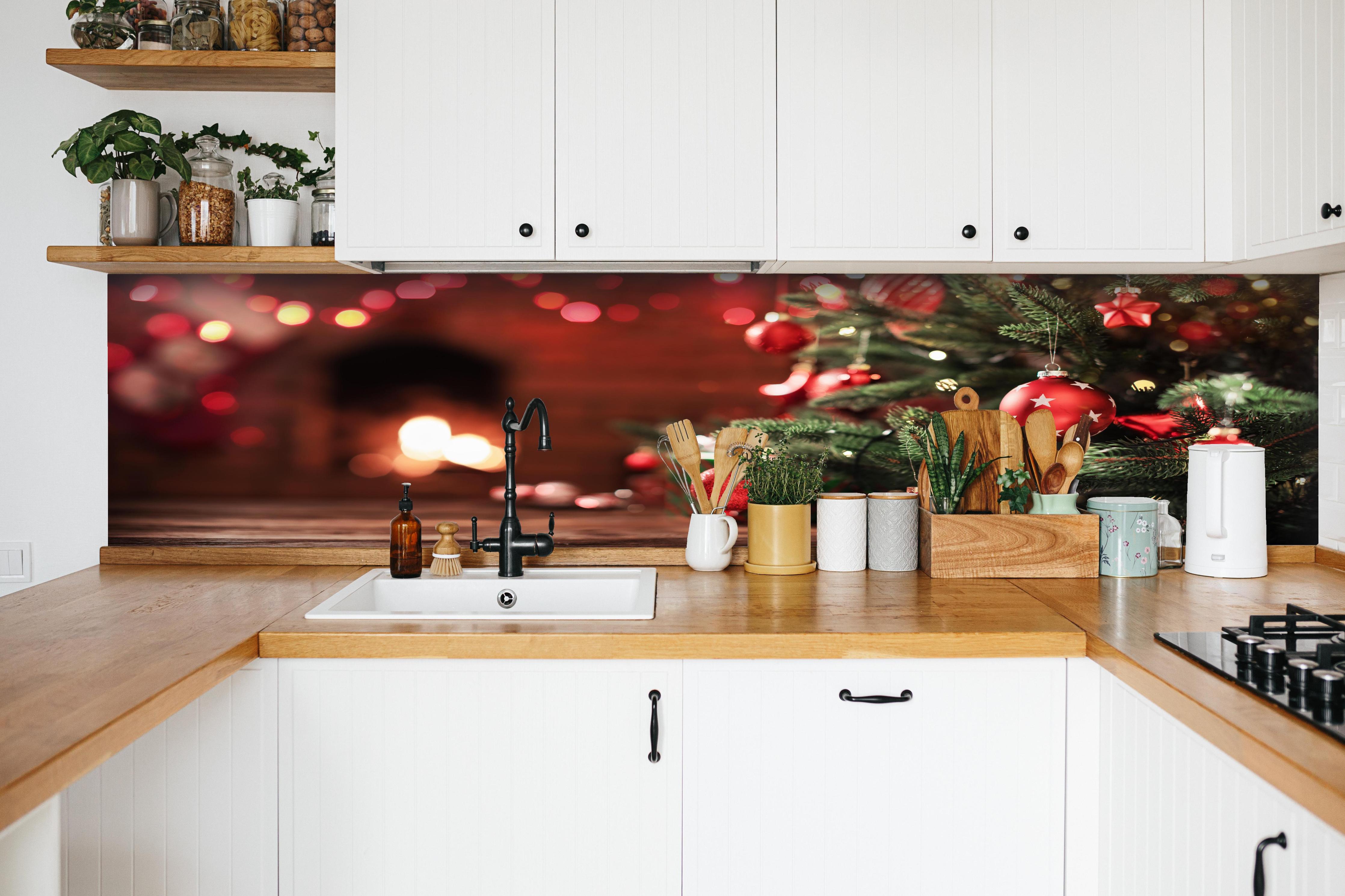 Küche - Weihnachtsbaum mit Dekorationen hinter weißen Hochglanz-Küchenregalen und schwarzem Wasserhahn