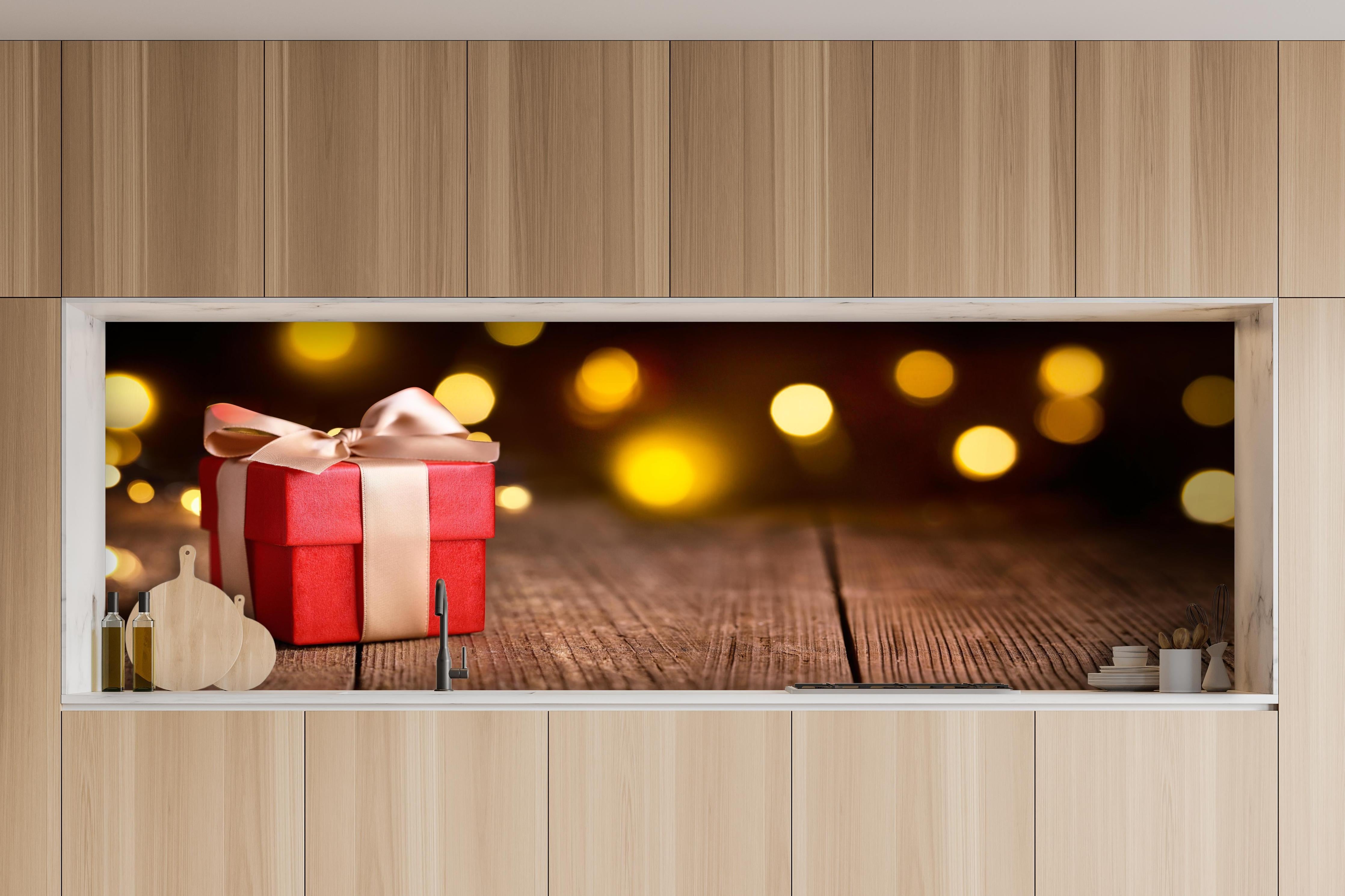 Küche - Weihnachtsgeschenk auf festlichem Hintergrund hinter weißen Hochglanz-Küchenregalen und schwarzem Wasserhahn