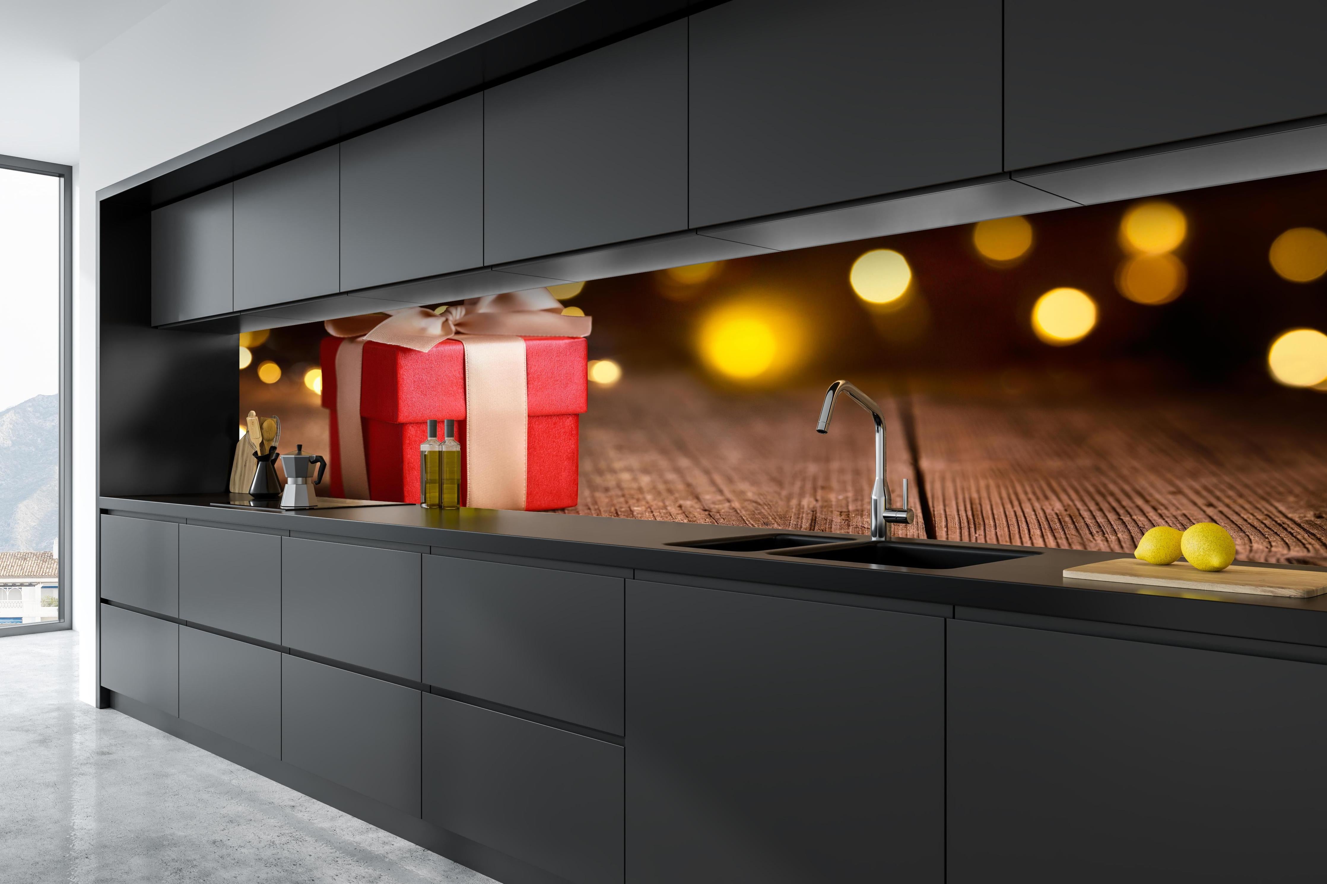 Küche - Weihnachtsgeschenk auf festlichem Hintergrund hinter weißen Hochglanz-Küchenregalen und schwarzem Wasserhahn