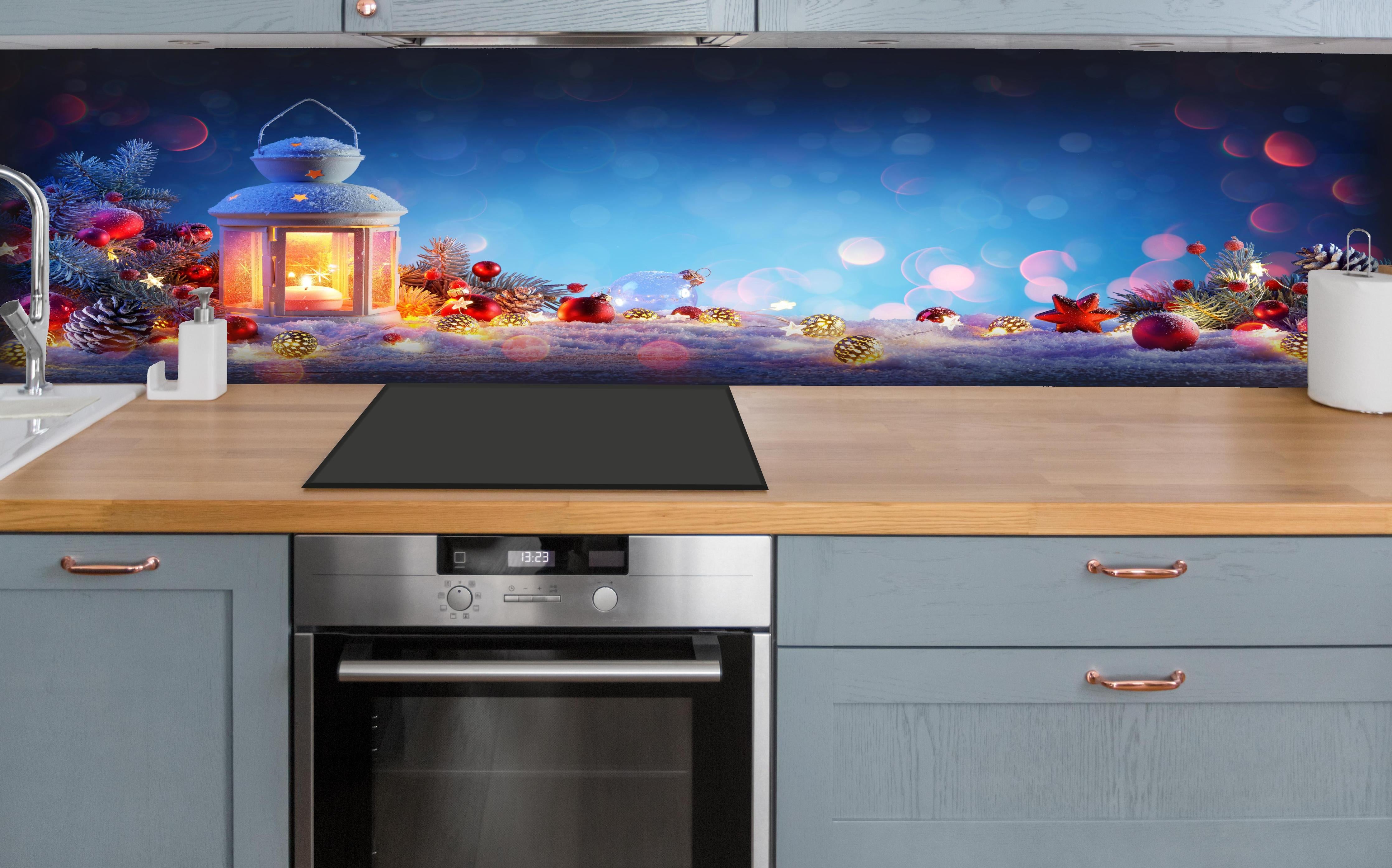 Küche - Weihnachtslaterne auf verschneiten Tisch hinter weißen Hochglanz-Küchenregalen und schwarzem Wasserhahn