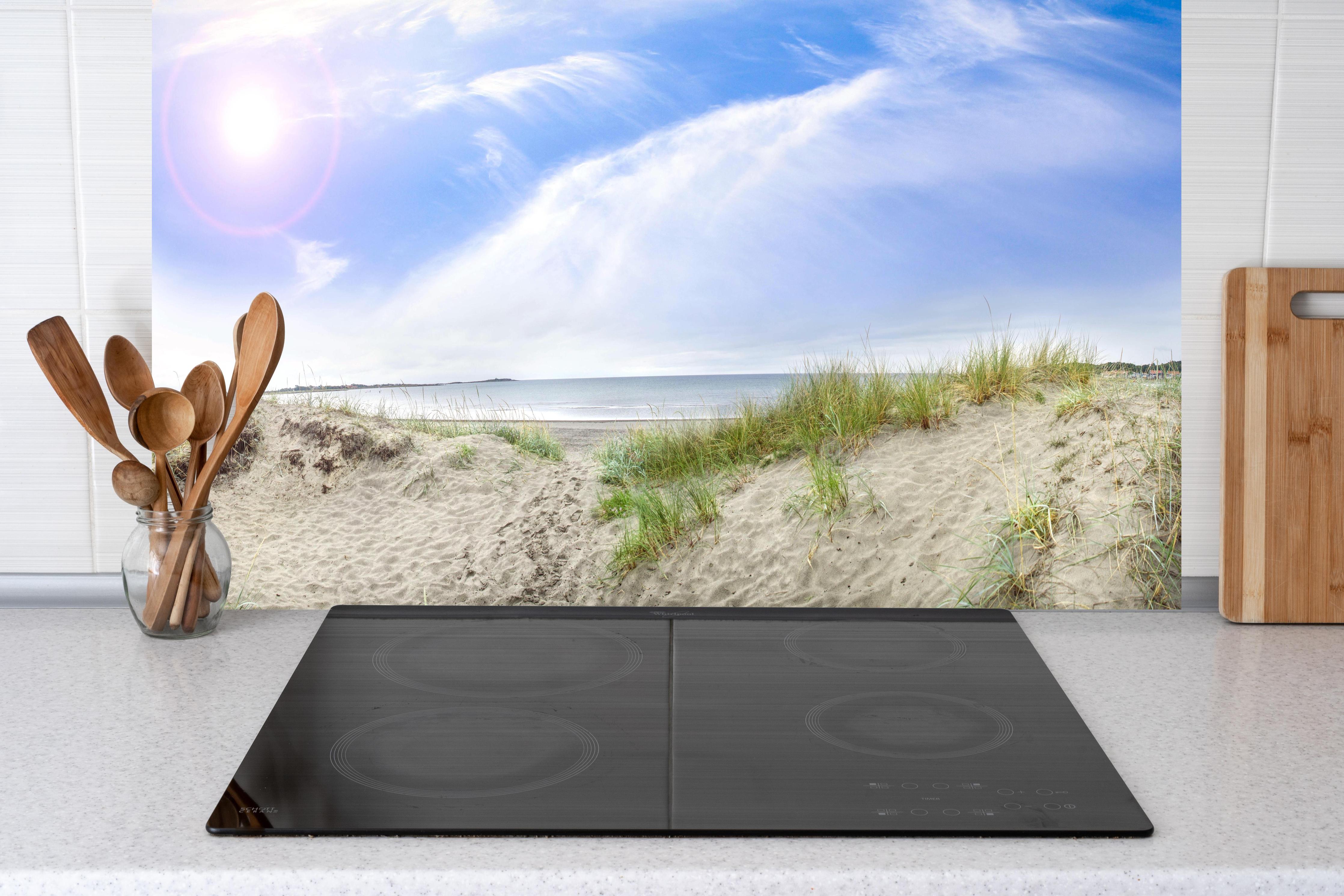 Küche - Weitläufige Strandlandschaft mit sanften Dünen, Himmel und ruhigem Wasser hinter weißen Hochglanz-Küchenregalen und schwarzem Wasserhahn