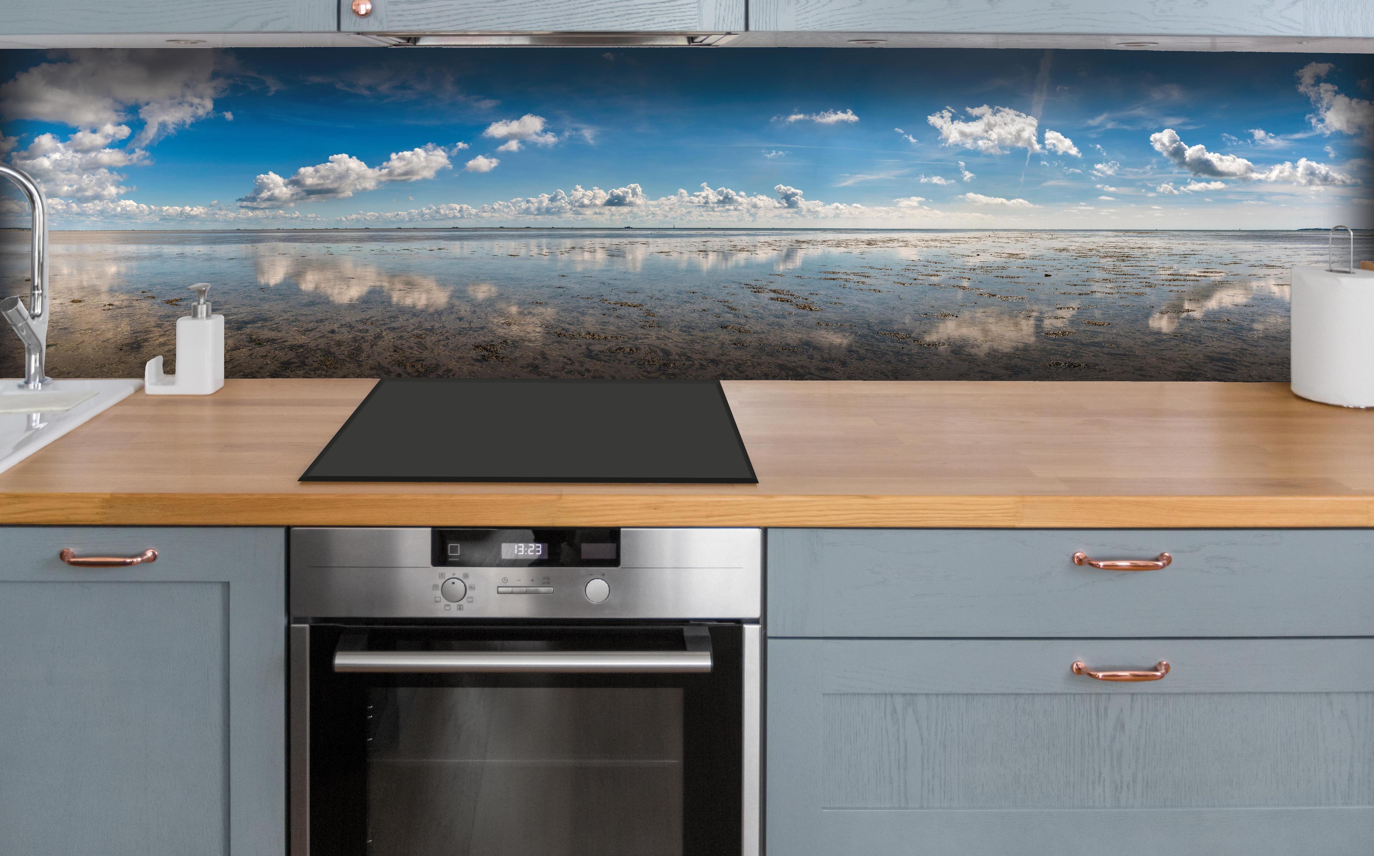 Küche - Weitläufiger Himmel und spiegelnde Wasseroberfläche mit Wolkenreflexionen hinter weißen Hochglanz-Küchenregalen und schwarzem Wasserhahn