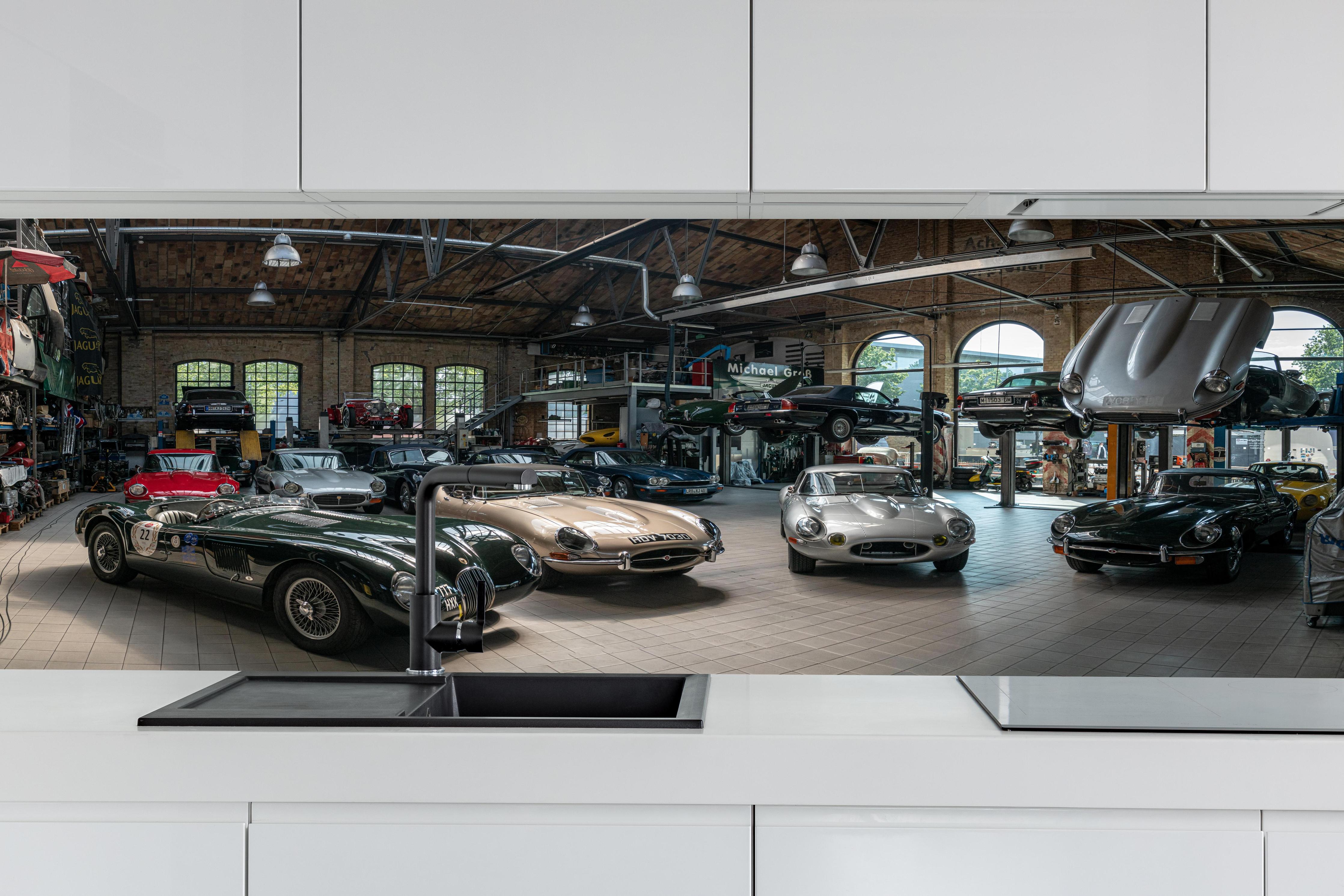 Küche - Werkstatt für die Reparatur und Wartung englischer Retro-Klassiker hinter weißen Hochglanz-Küchenregalen und schwarzem Wasserhahn