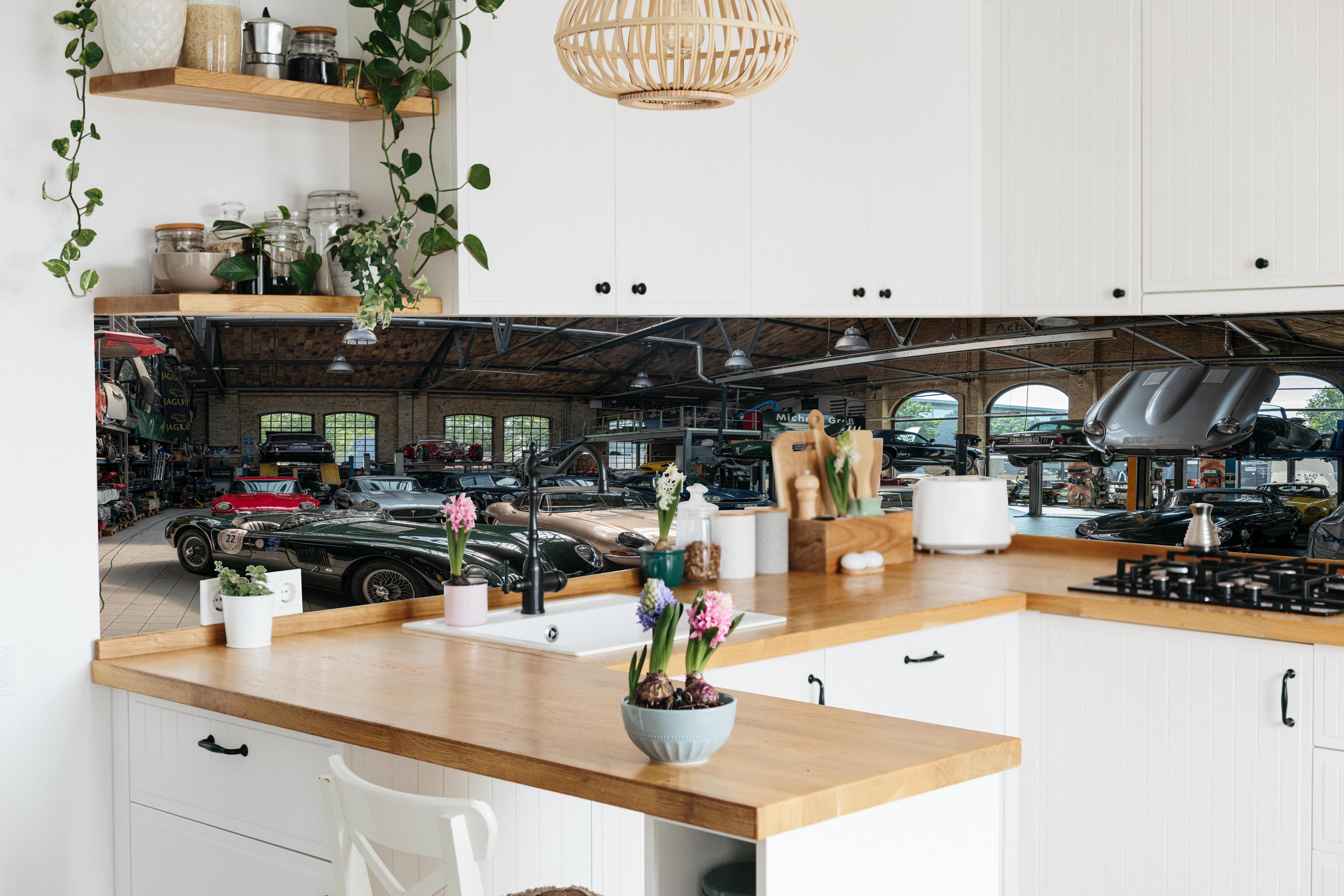 Küche - Werkstatt für die Reparatur und Wartung englischer Retro-Klassiker hinter weißen Hochglanz-Küchenregalen und schwarzem Wasserhahn