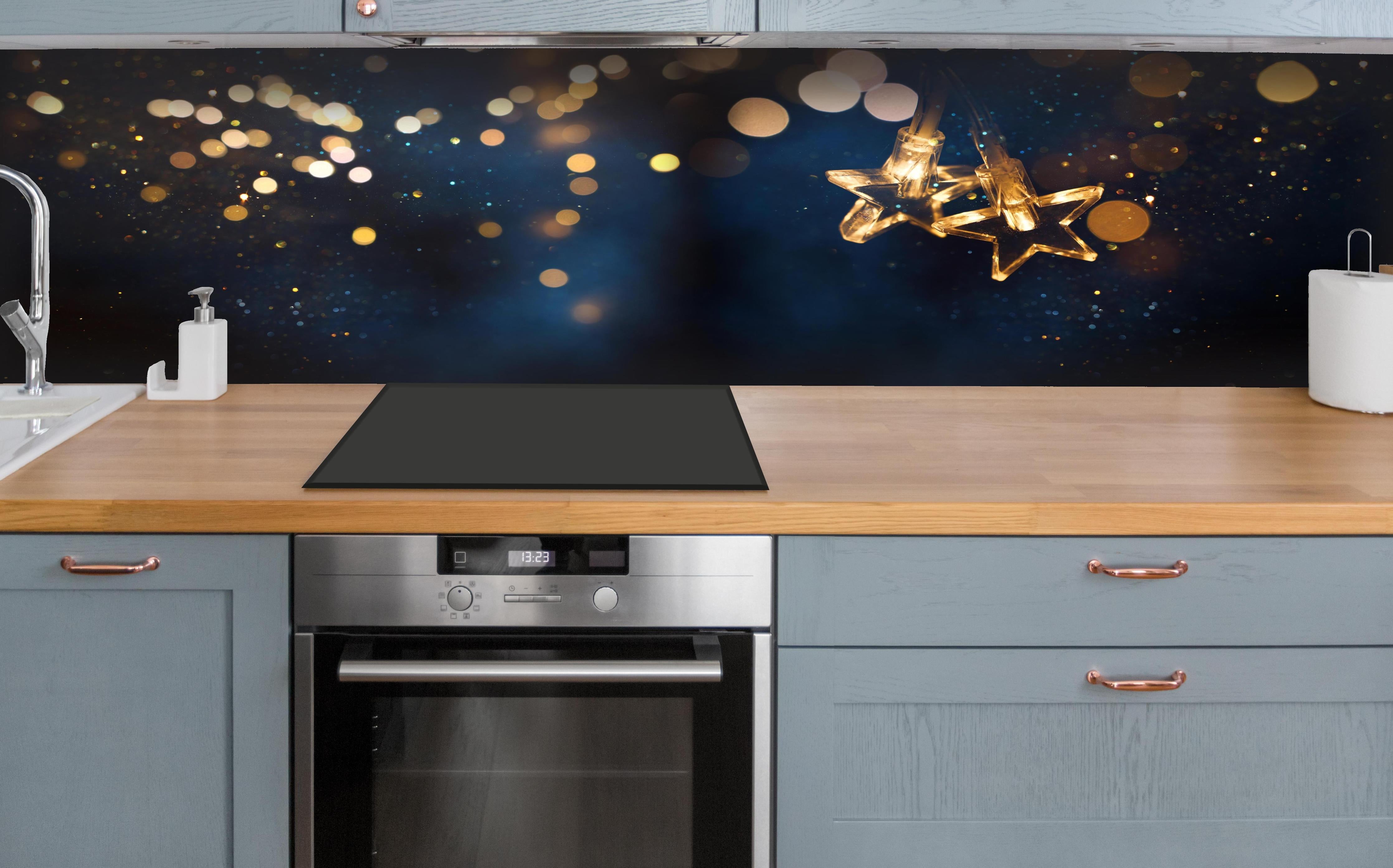 Küche - Winterliche Dekoration - Lichterkette hinter weißen Hochglanz-Küchenregalen und schwarzem Wasserhahn