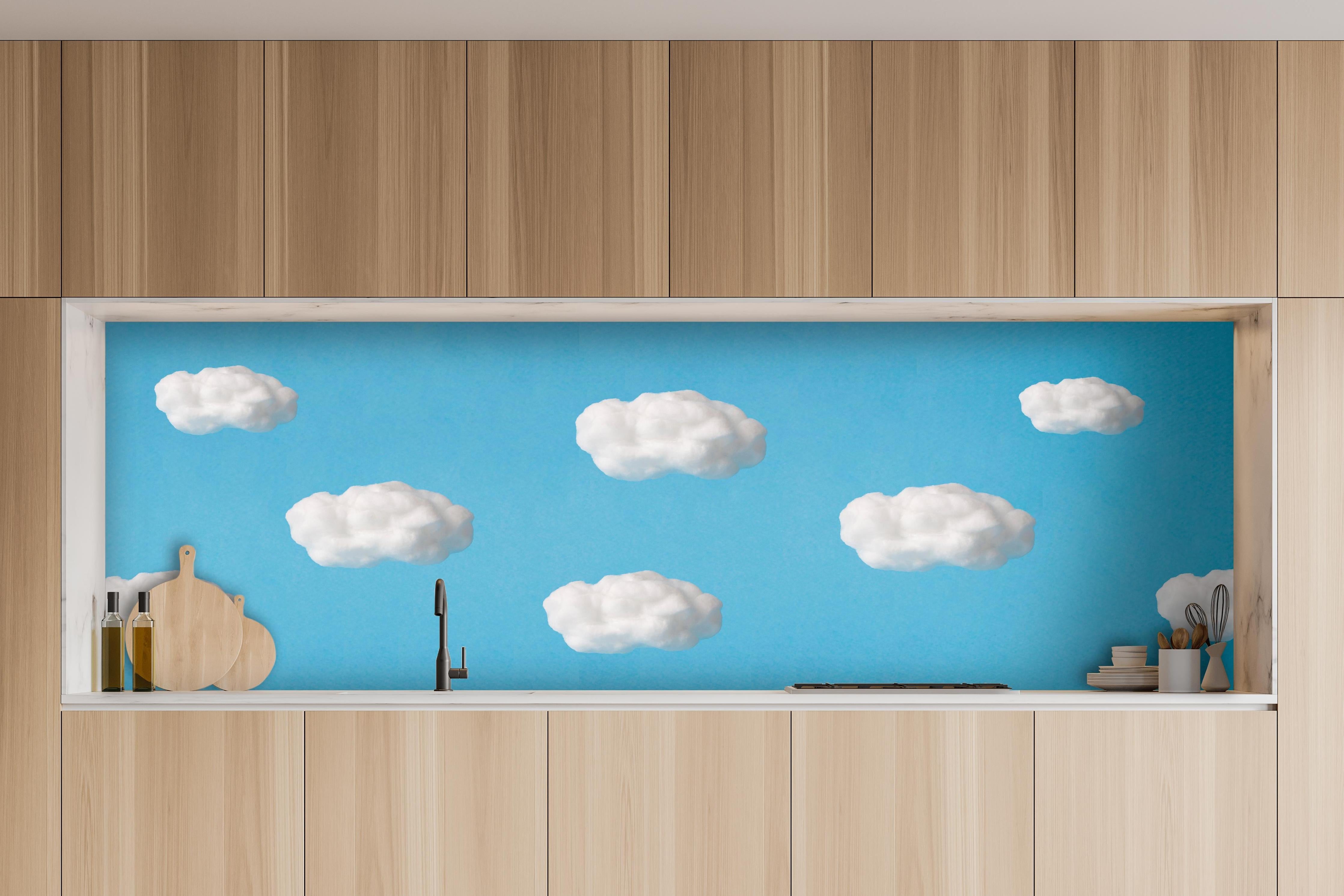 Küche - Wolke aus Watte auf himmelblauem Hintergrund hinter weißen Hochglanz-Küchenregalen und schwarzem Wasserhahn