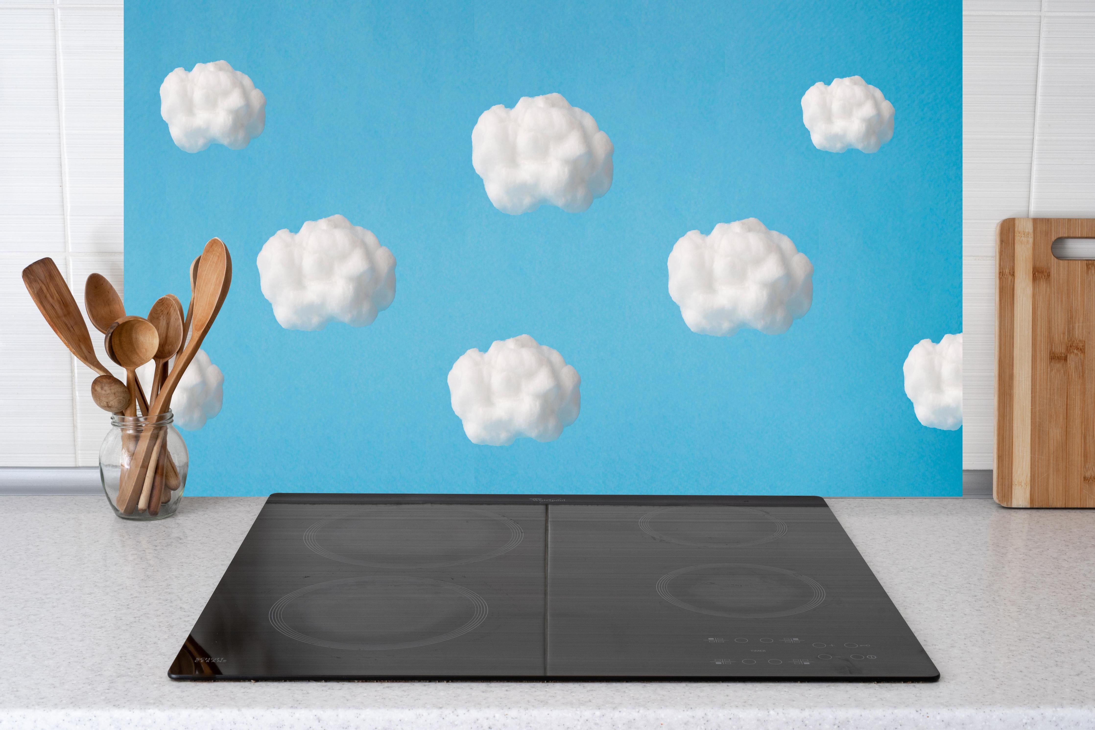 Küche - Wolke aus Watte auf himmelblauem Hintergrund hinter weißen Hochglanz-Küchenregalen und schwarzem Wasserhahn