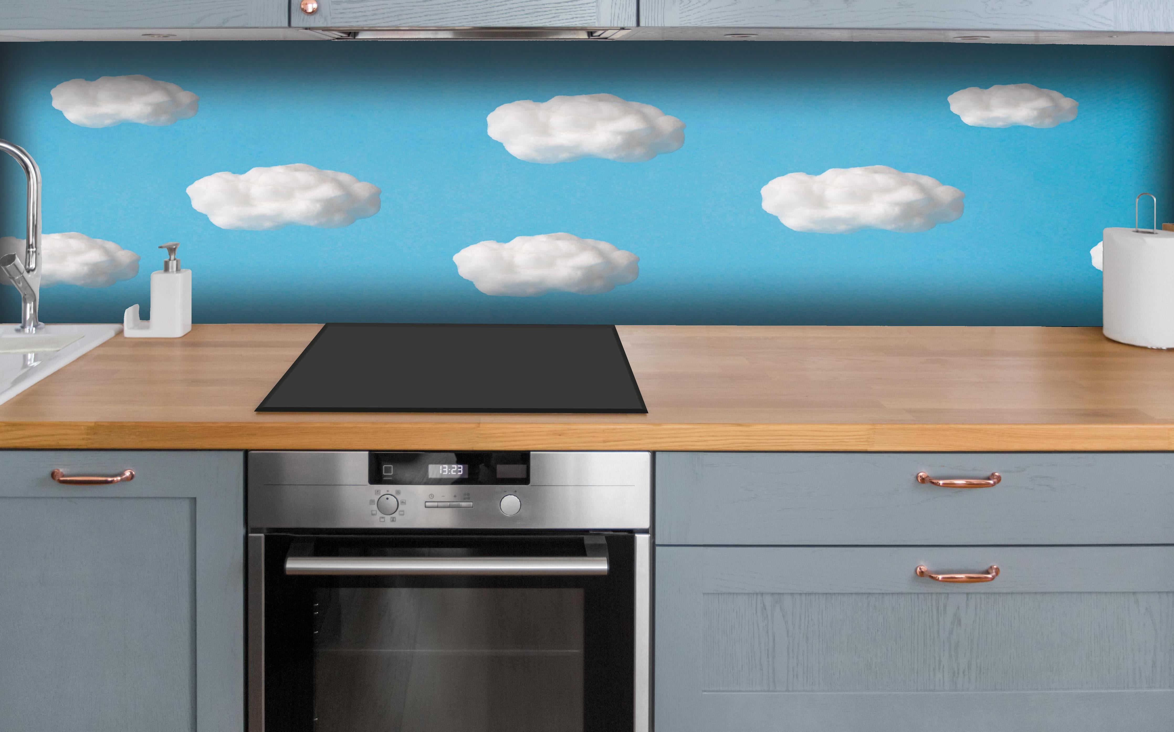 Küche - Wolke aus Watte auf himmelblauem Hintergrund hinter weißen Hochglanz-Küchenregalen und schwarzem Wasserhahn