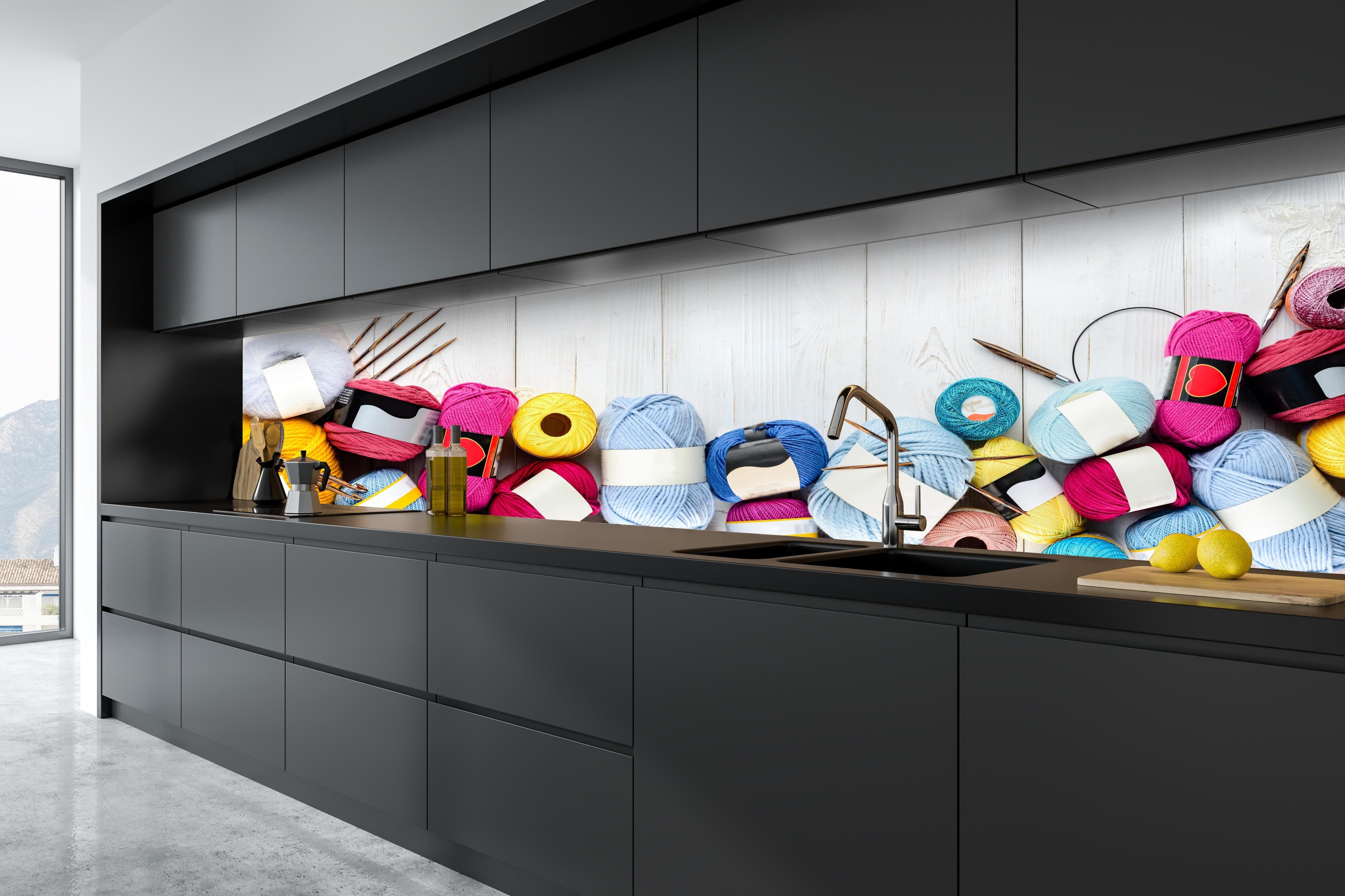 Küche - Wolle und Stricknadeln auf Holzhintergrund hinter weißen Hochglanz-Küchenregalen und schwarzem Wasserhahn