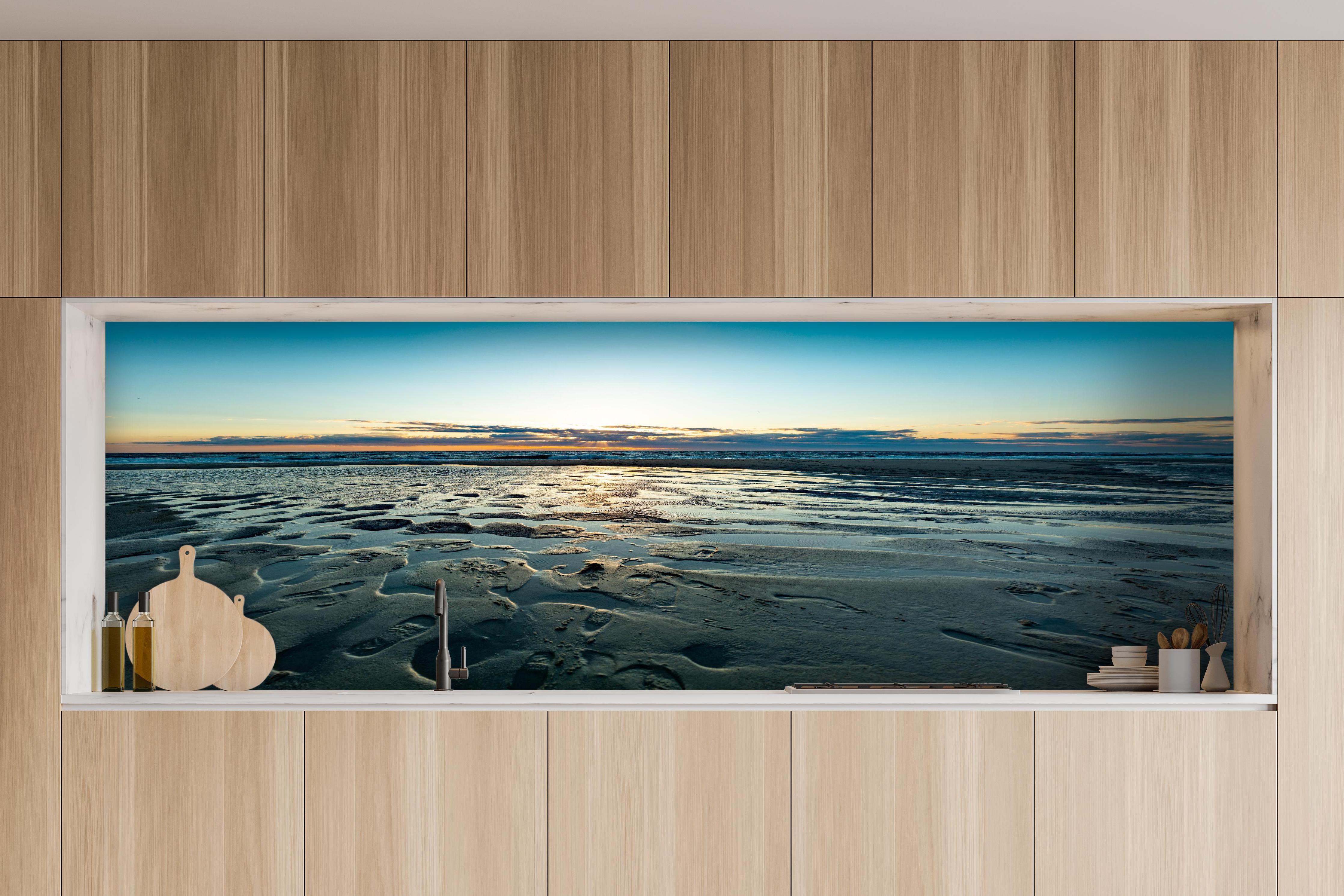 Küche - Wunderschöne blaue und orange Strandlandschaft mit Sonnenuntergang hinter weißen Hochglanz-Küchenregalen und schwarzem Wasserhahn