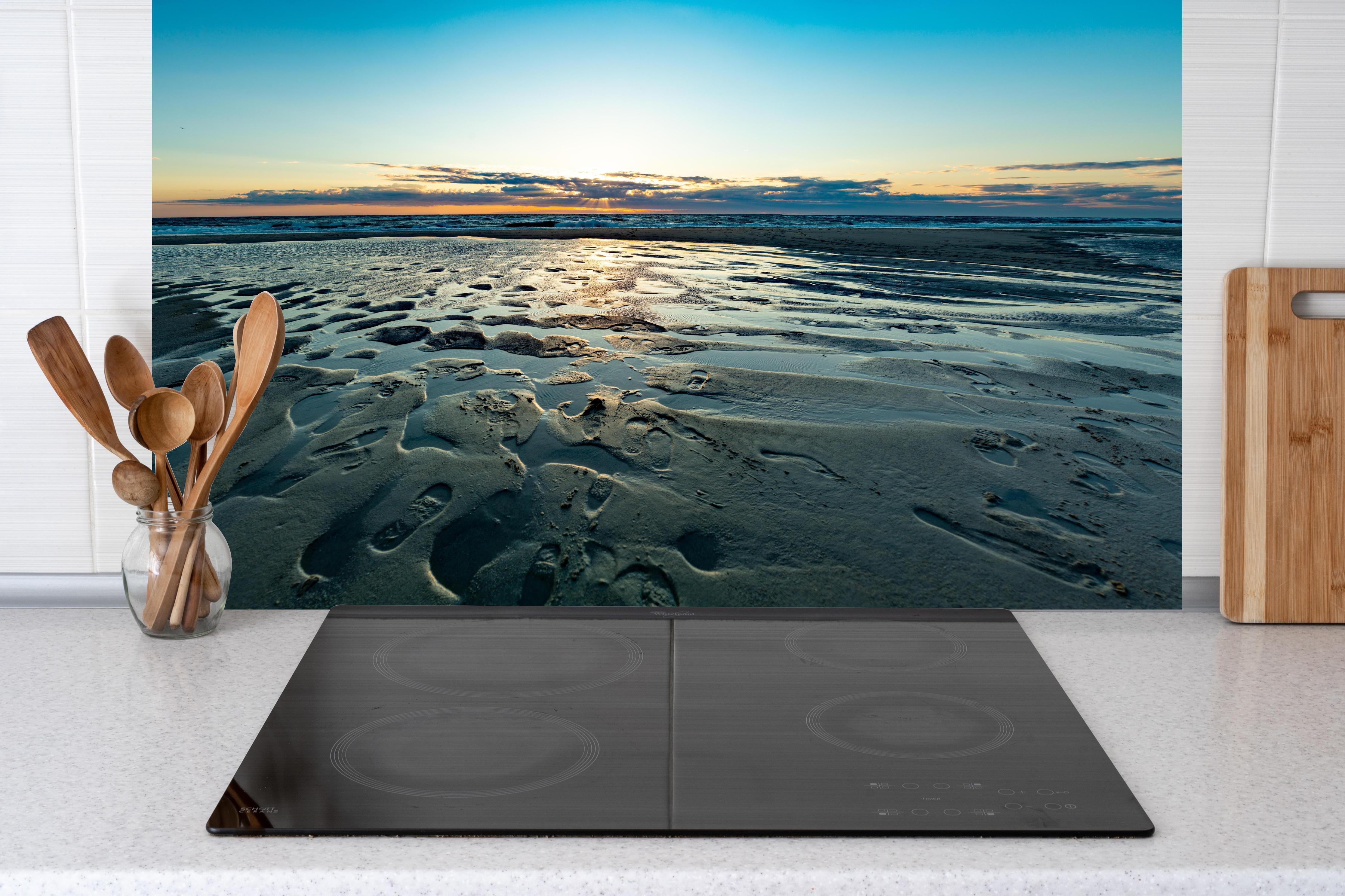 Küche - Wunderschöne blaue und orange Strandlandschaft mit Sonnenuntergang hinter weißen Hochglanz-Küchenregalen und schwarzem Wasserhahn