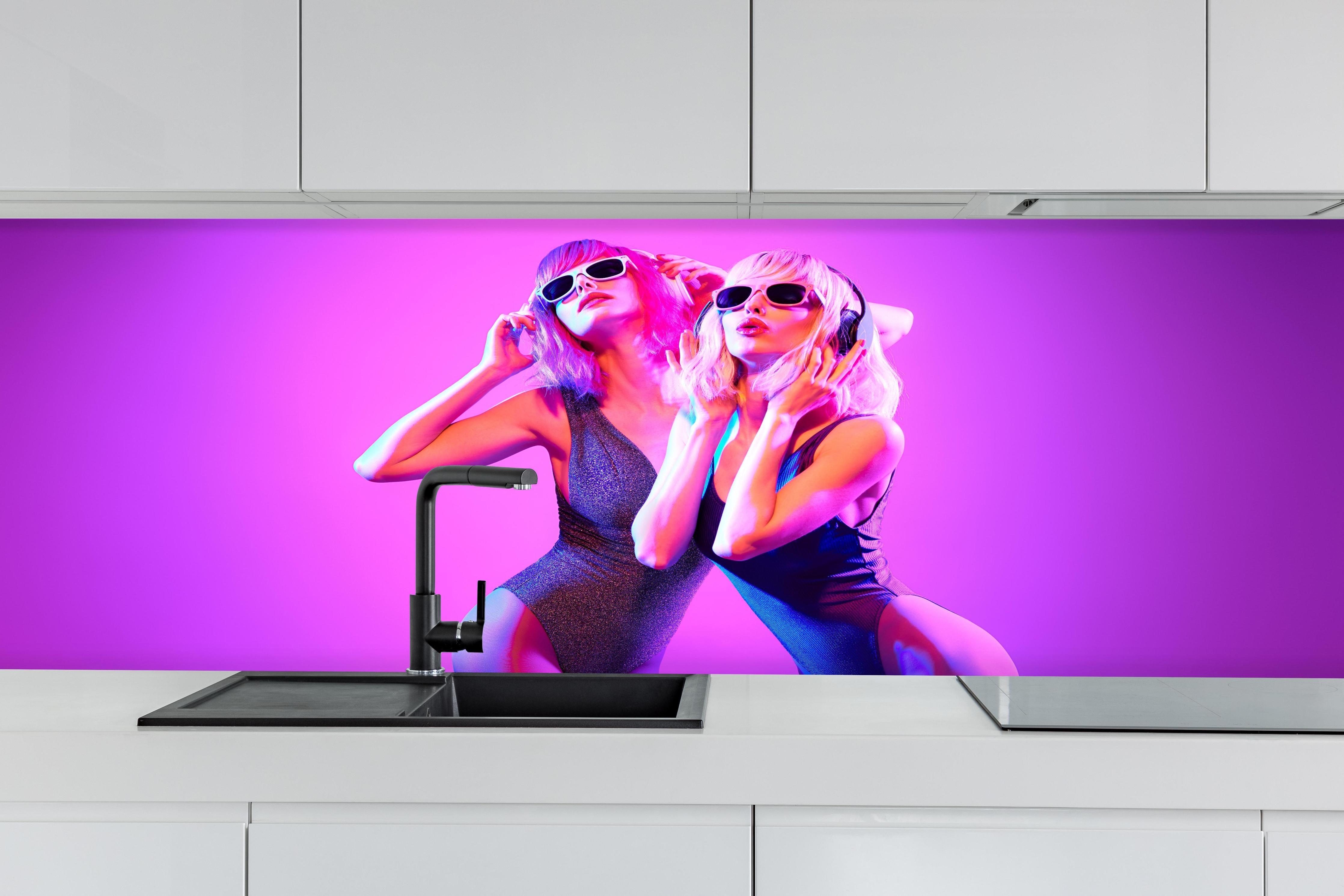 Küche - Zwei DJ Fitness Frau in bunten Neonlicht. Disco hinter weißen Hochglanz-Küchenregalen und schwarzem Wasserhahn