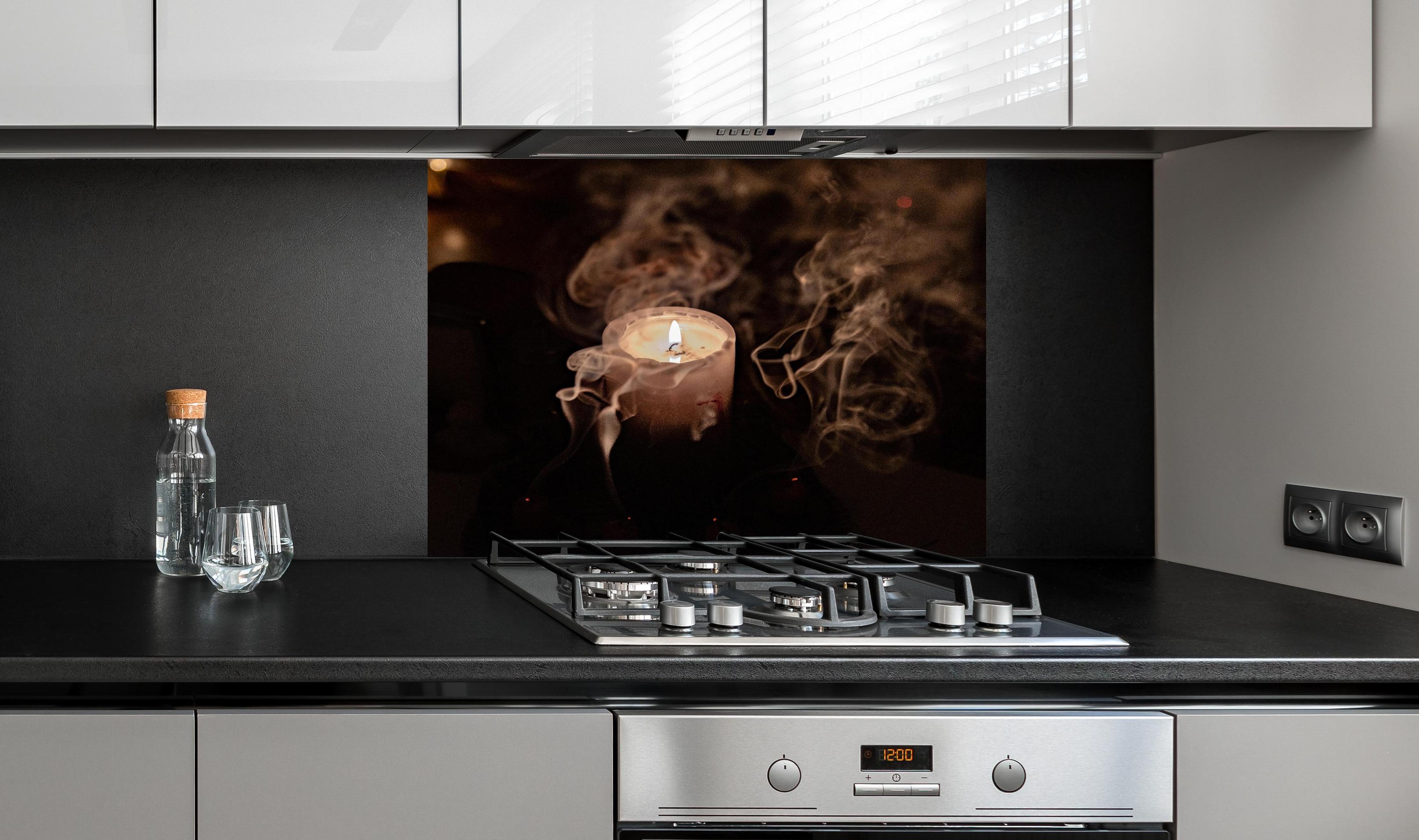 Spritzschutz - Mystischer Kerzenrauch bei brennender Kerze hinter einem Cerankochfeld zwischen Holz-Kochutensilien