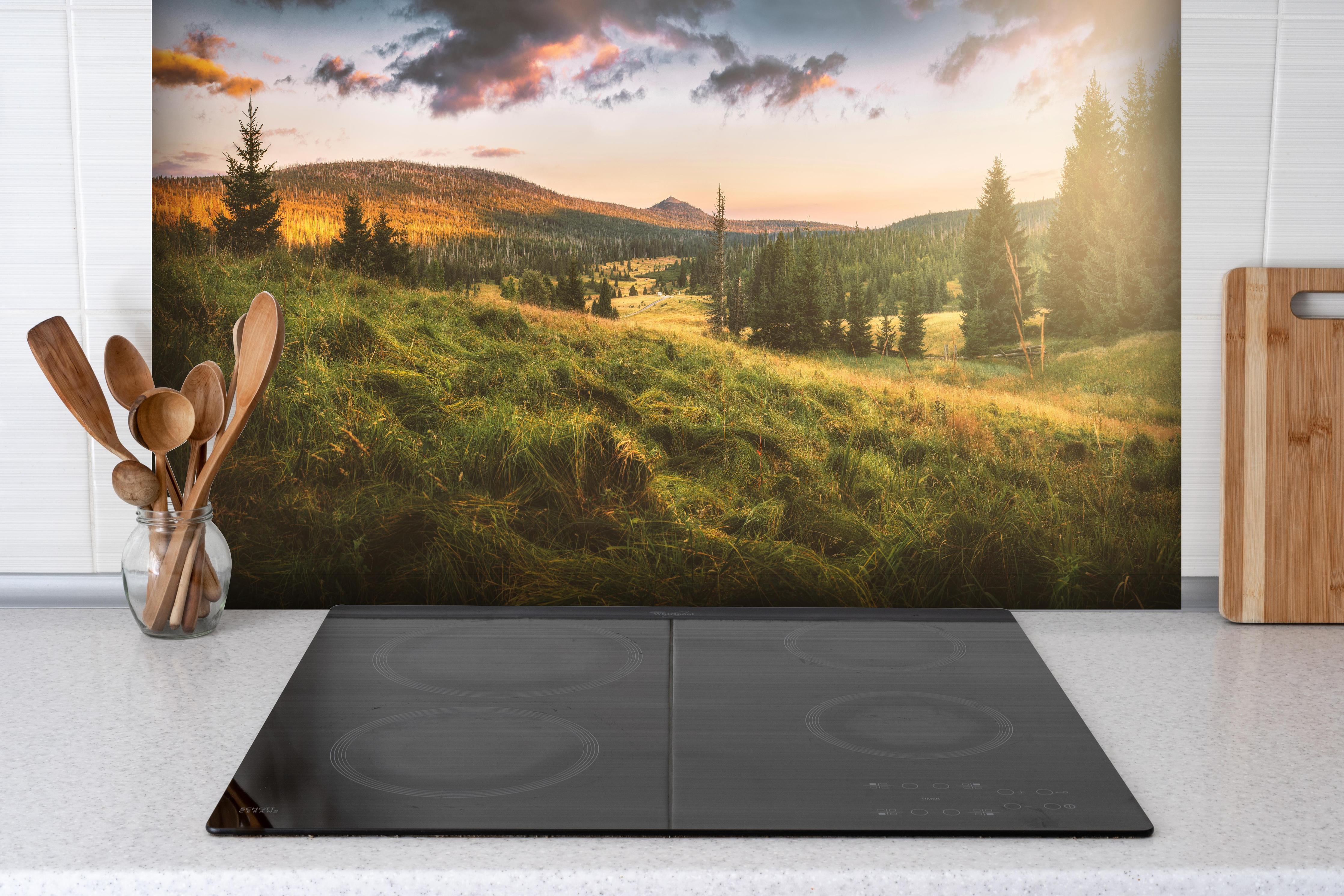 Spritzschutz - Abendlicher Berg Luzný - Tschechien hinter einem Cerankochfeld zwischen Holz-Kochutensilien