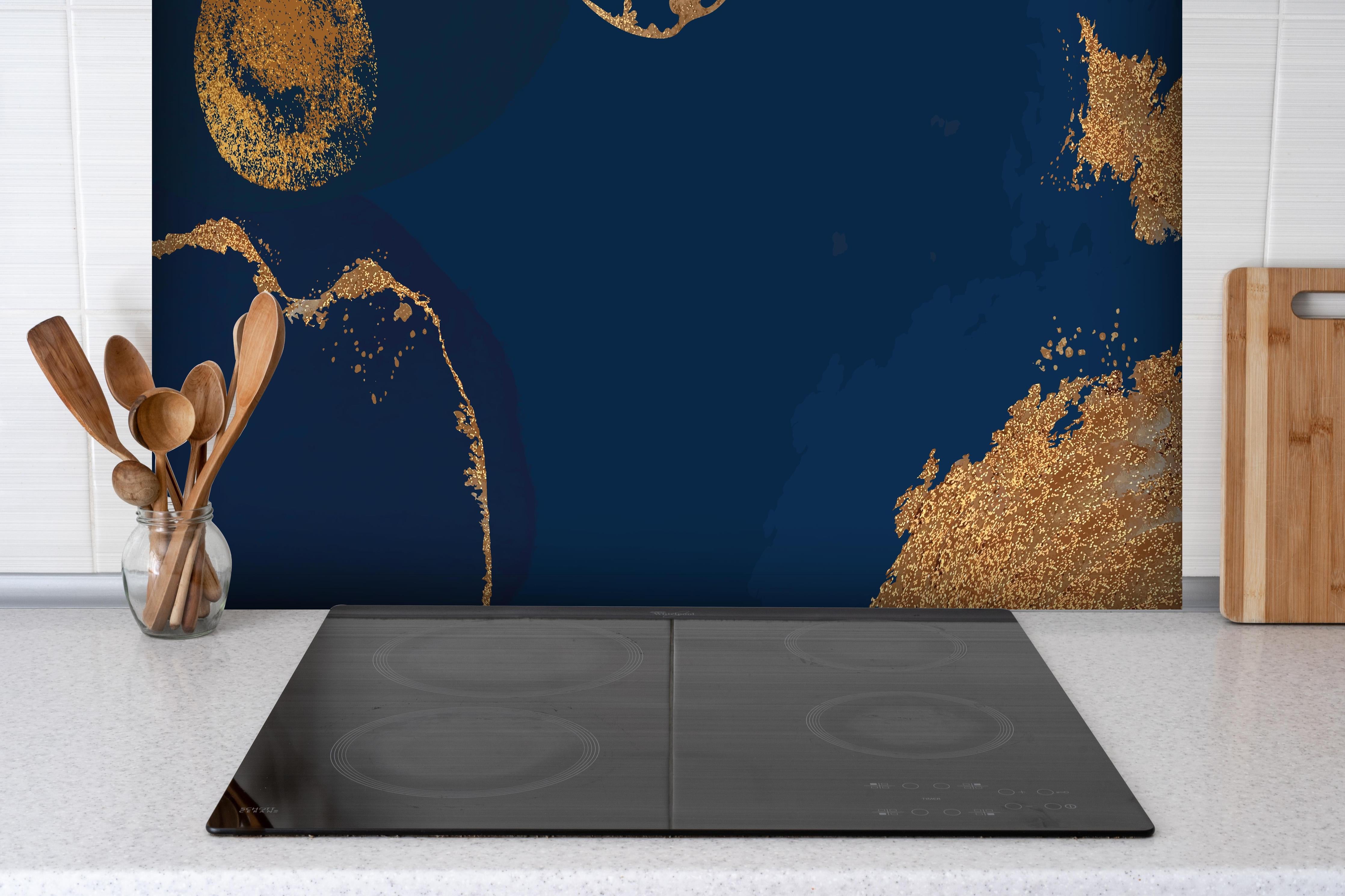 Spritzschutz - Abstract Art Dunkelheit mit Goldflimmer hinter einem Cerankochfeld zwischen Holz-Kochutensilien