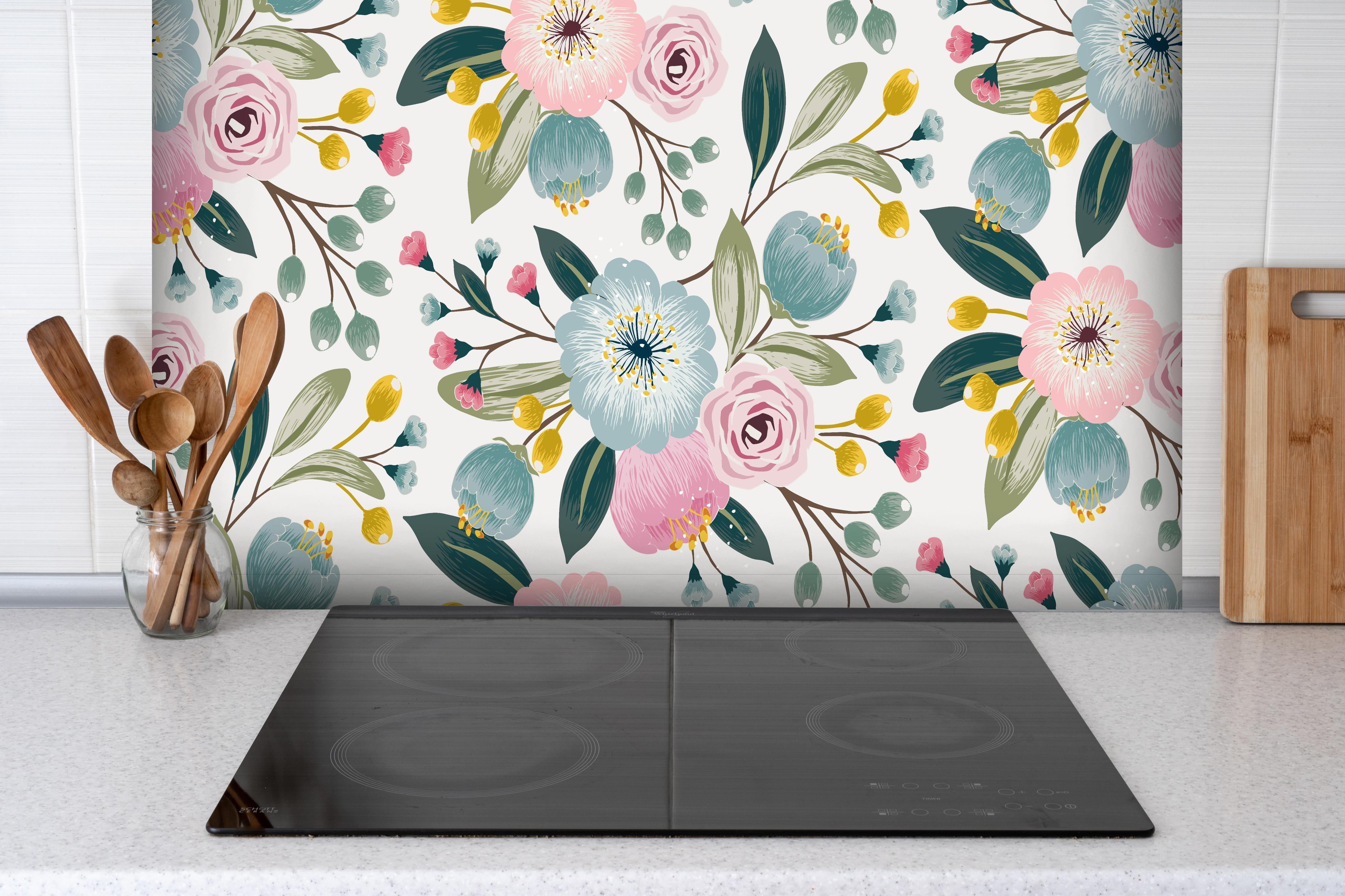 Spritzschutz - Abstrakte Blumenmuster in Rosa und Hellblau hinter einem Cerankochfeld zwischen Holz-Kochutensilien