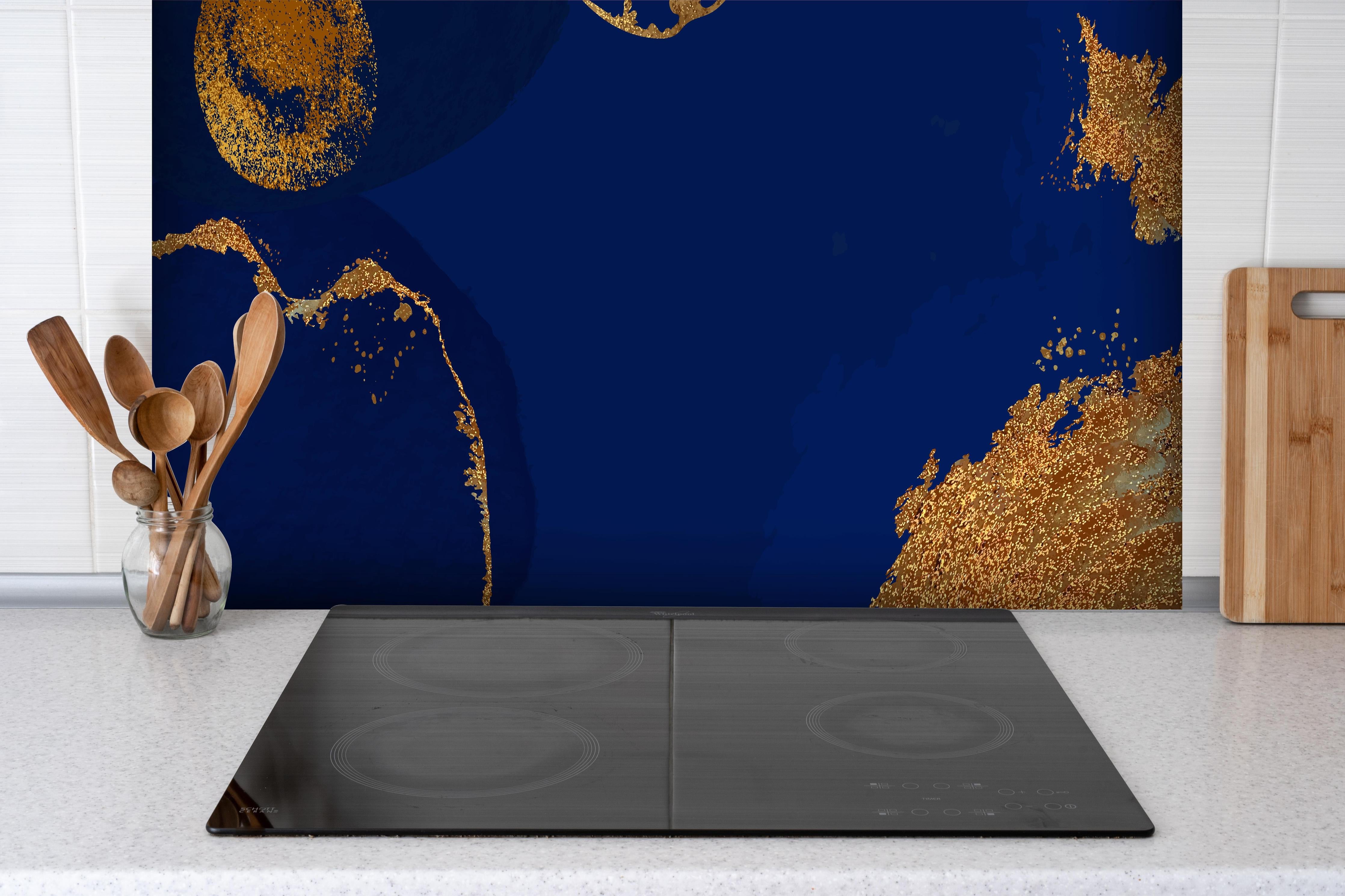 Spritzschutz - Abstrakte Kunst in Gold-und Blautönen hinter einem Cerankochfeld zwischen Holz-Kochutensilien