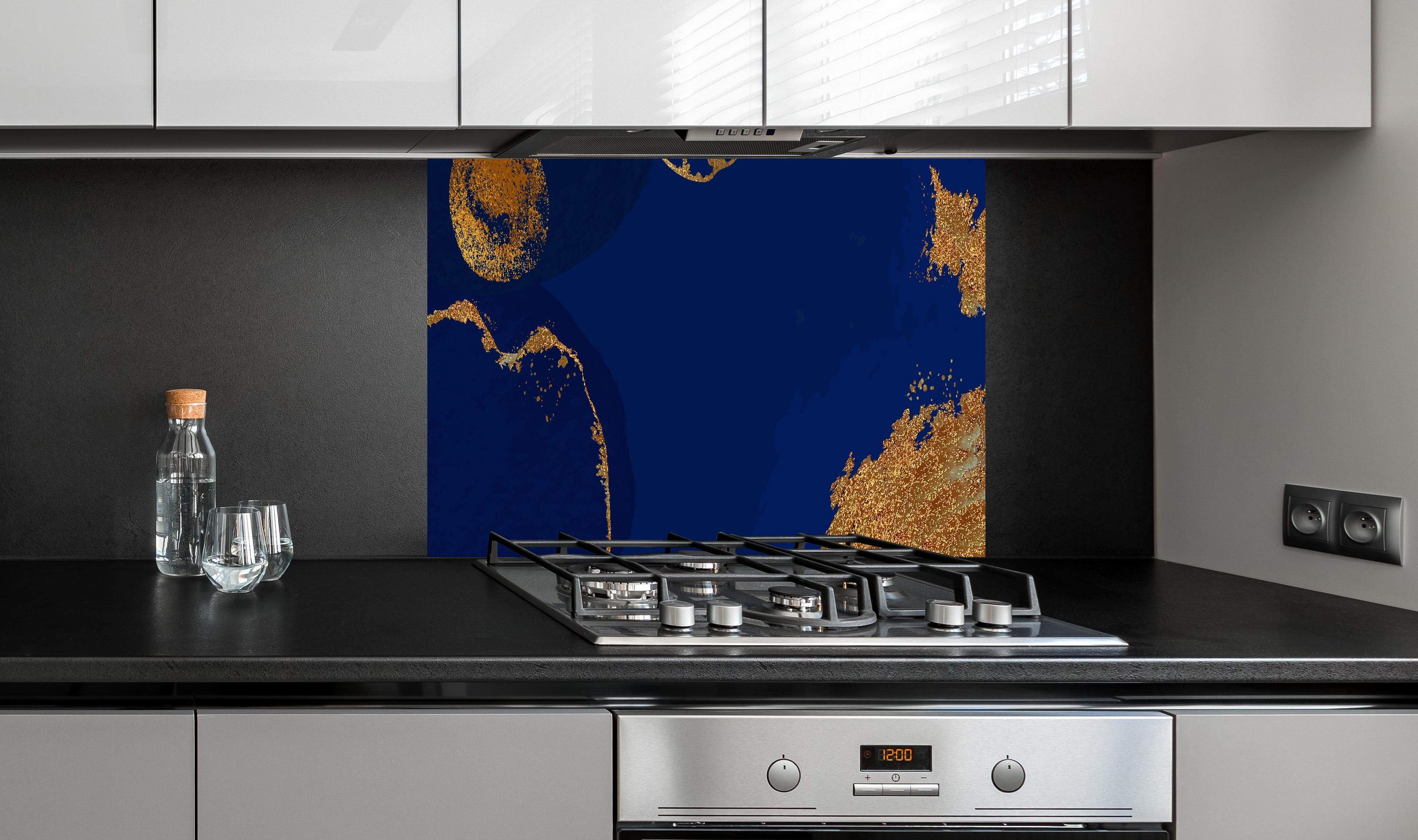 Spritzschutz - Abstrakte Kunst in Gold-und Blautönen hinter einem Cerankochfeld zwischen Holz-Kochutensilien