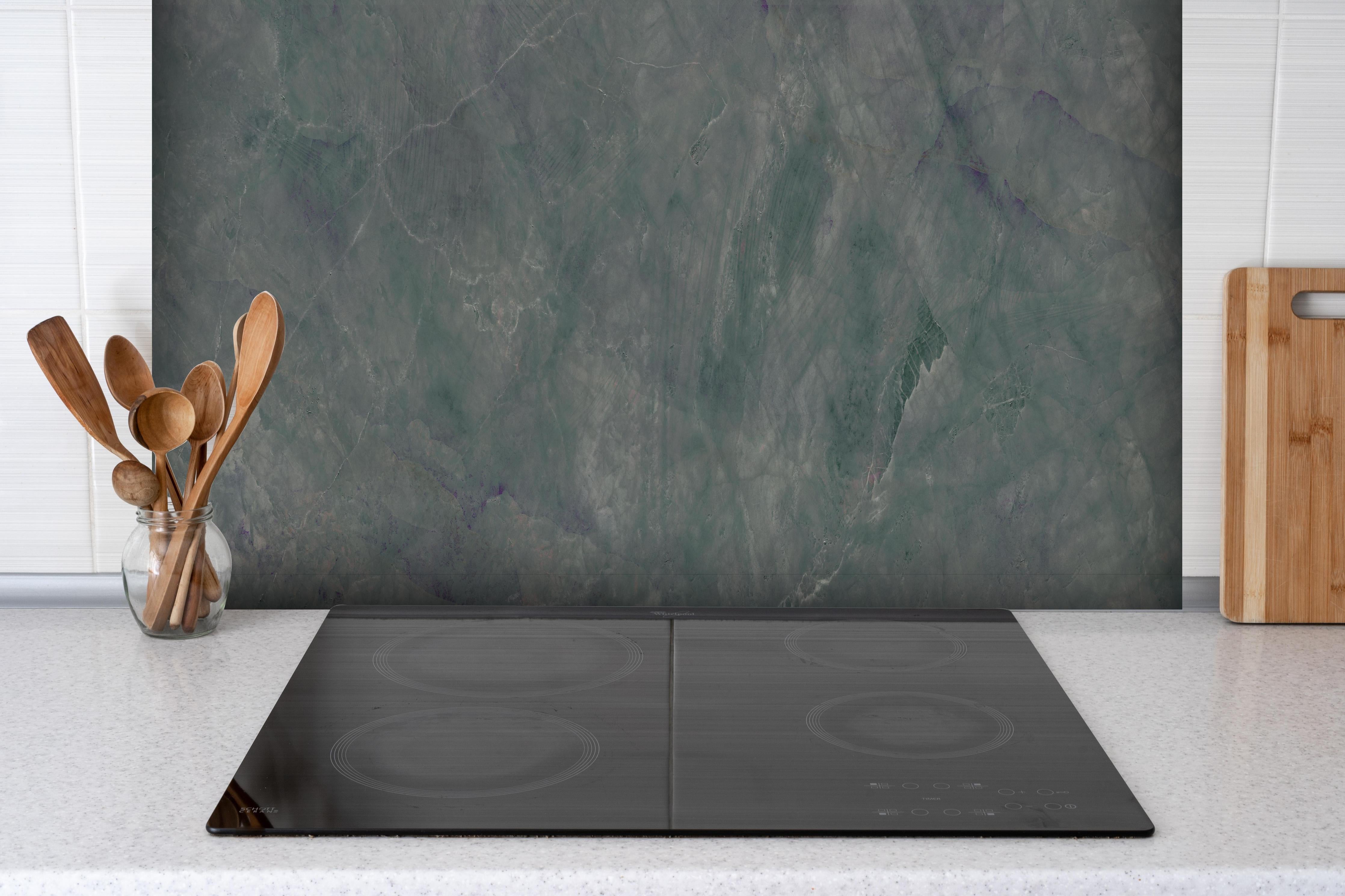 Spritzschutz - Abstrakte Marmormischung hinter einem Cerankochfeld zwischen Holz-Kochutensilien