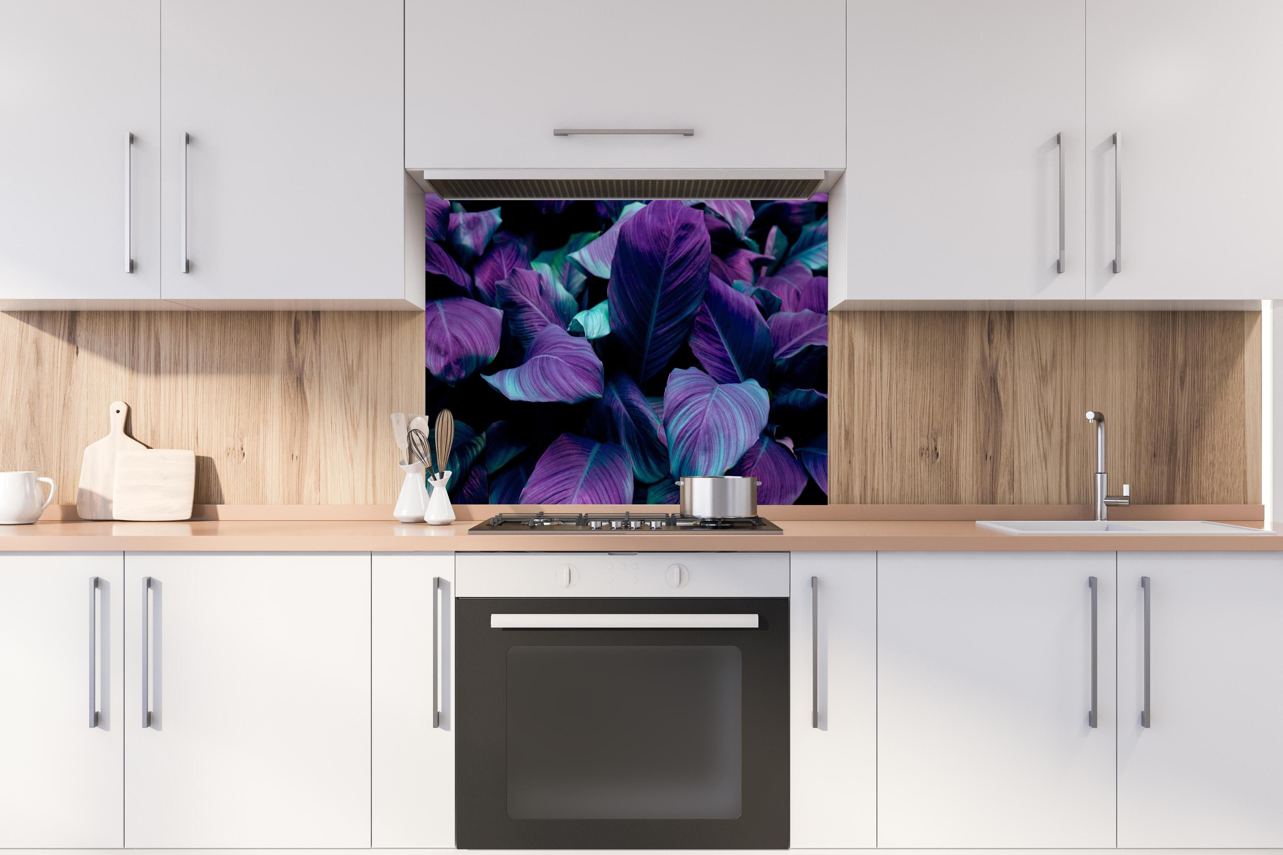 Spritzschutz - Abstrakte Tropenblätter in dunklen Farbtönen hinter einem Cerankochfeld zwischen Holz-Kochutensilien