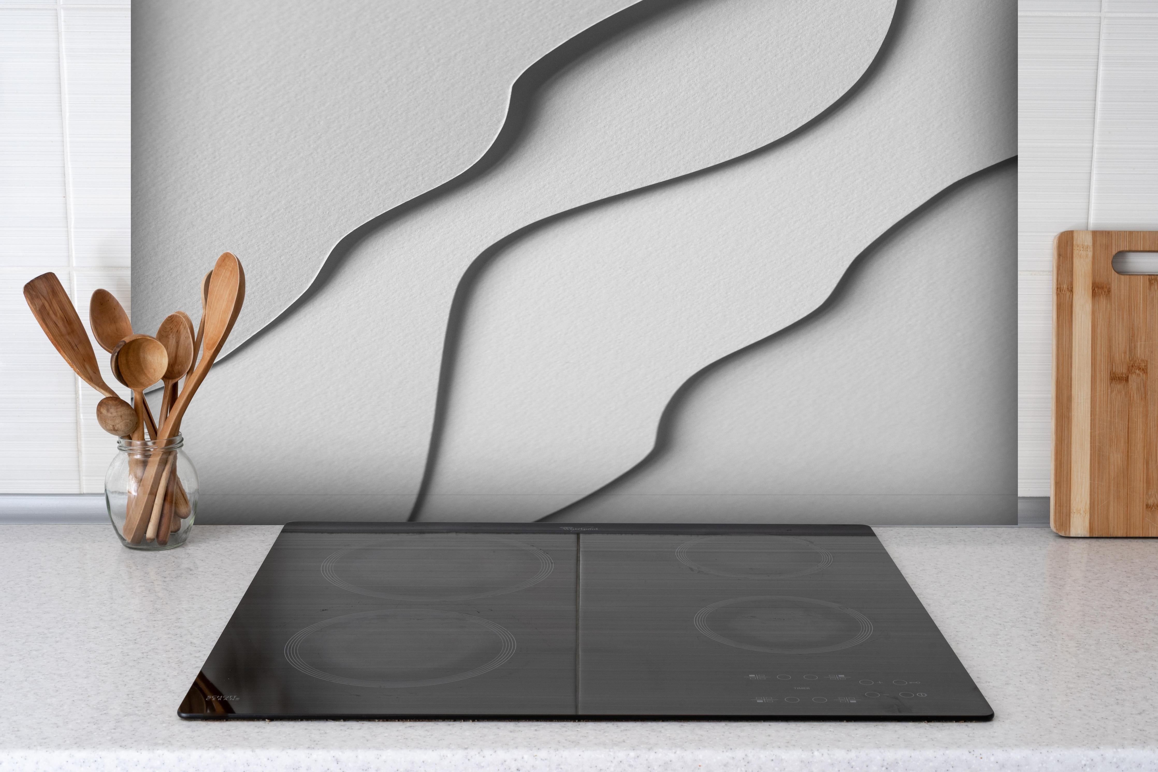 Spritzschutz - Abstrakte monochrome Papierwellen in Pastell hinter einem Cerankochfeld zwischen Holz-Kochutensilien