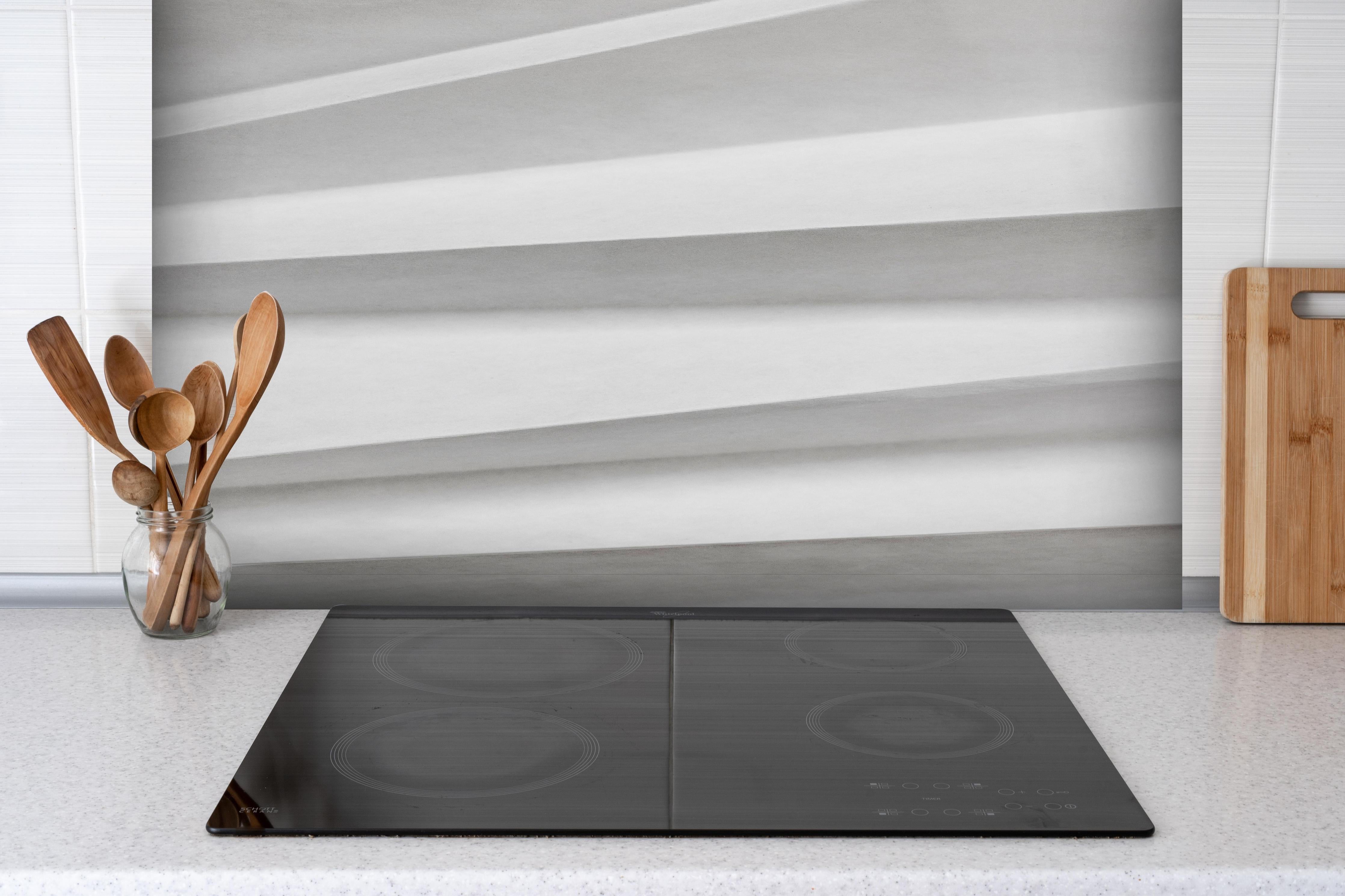 Spritzschutz - Abstrakte weiβe Papierkunst mit Grautönen hinter einem Cerankochfeld zwischen Holz-Kochutensilien