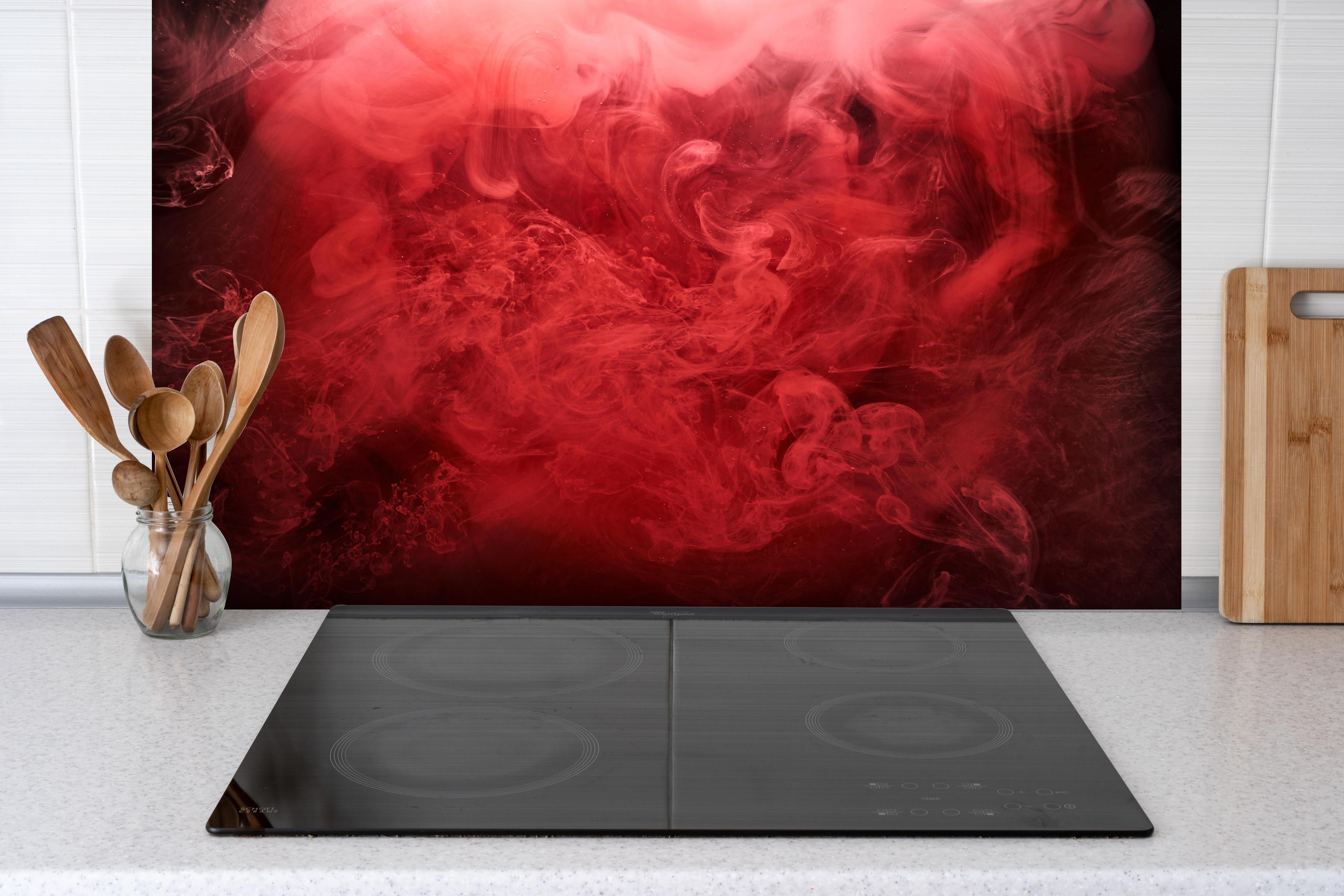 Spritzschutz - Abstrakter roter Ozean hinter einem Cerankochfeld zwischen Holz-Kochutensilien