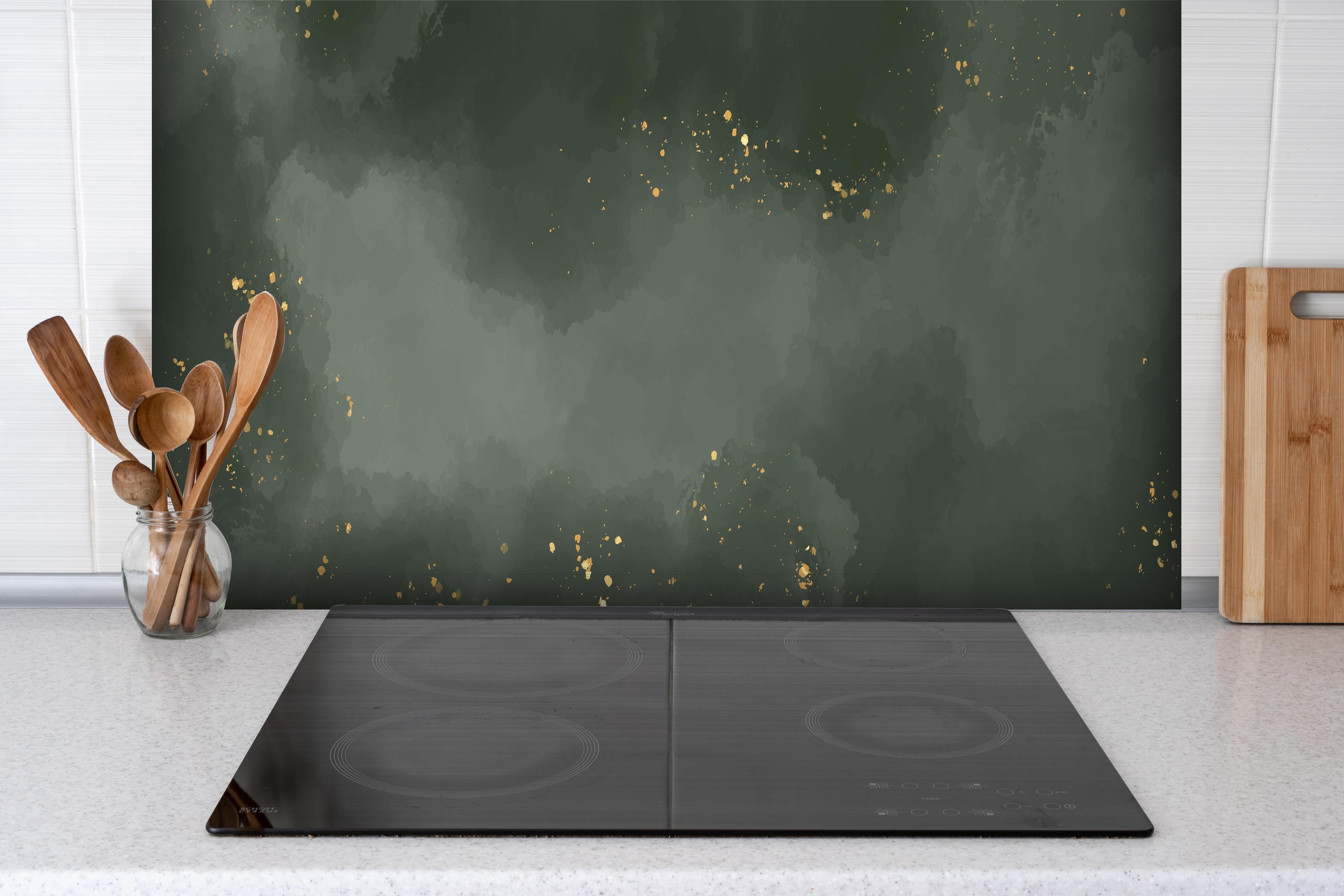 Spritzschutz - Abstraktes Muster in Dunkelgrün mit Gold hinter einem Cerankochfeld zwischen Holz-Kochutensilien