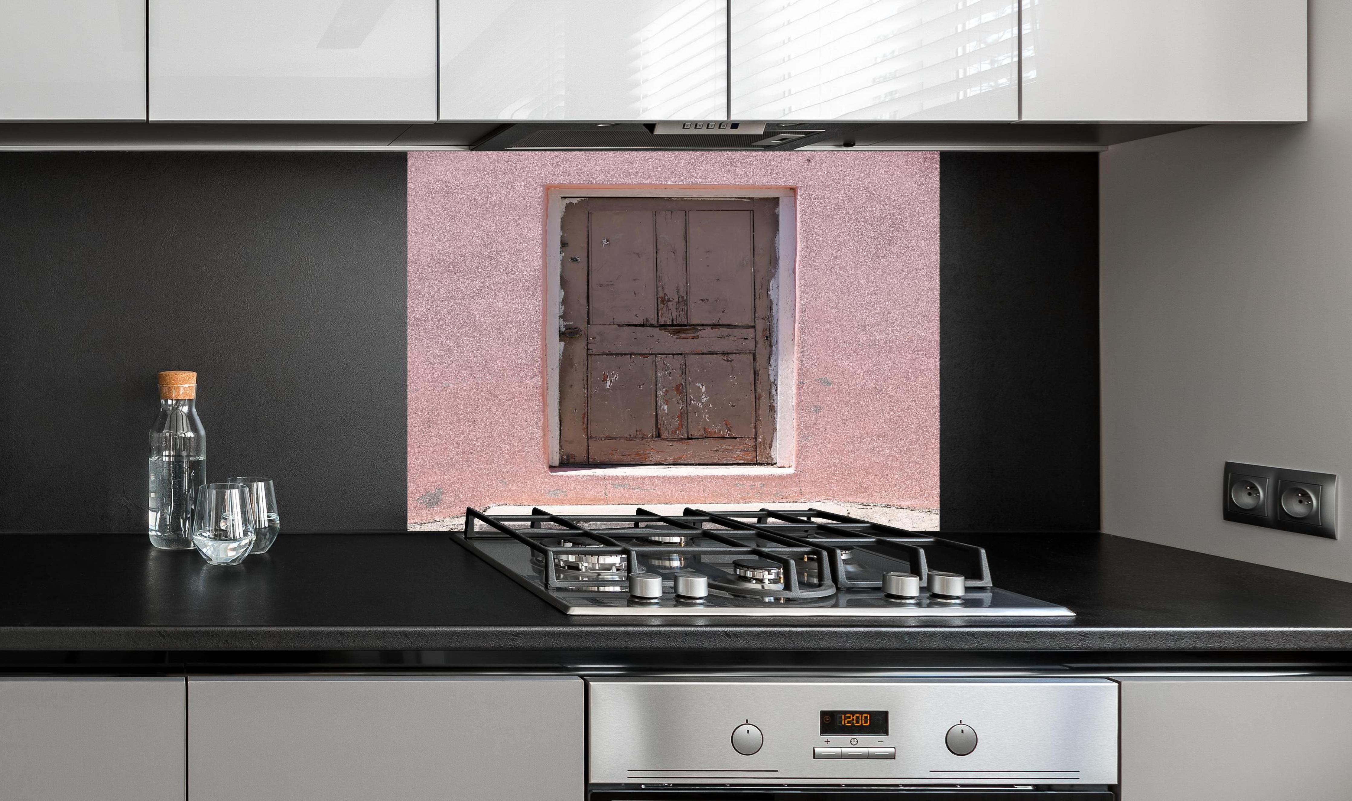 Spritzschutz - Alte Tür mit abblätternder Farbe an Rosa Wand hinter einem Cerankochfeld zwischen Holz-Kochutensilien