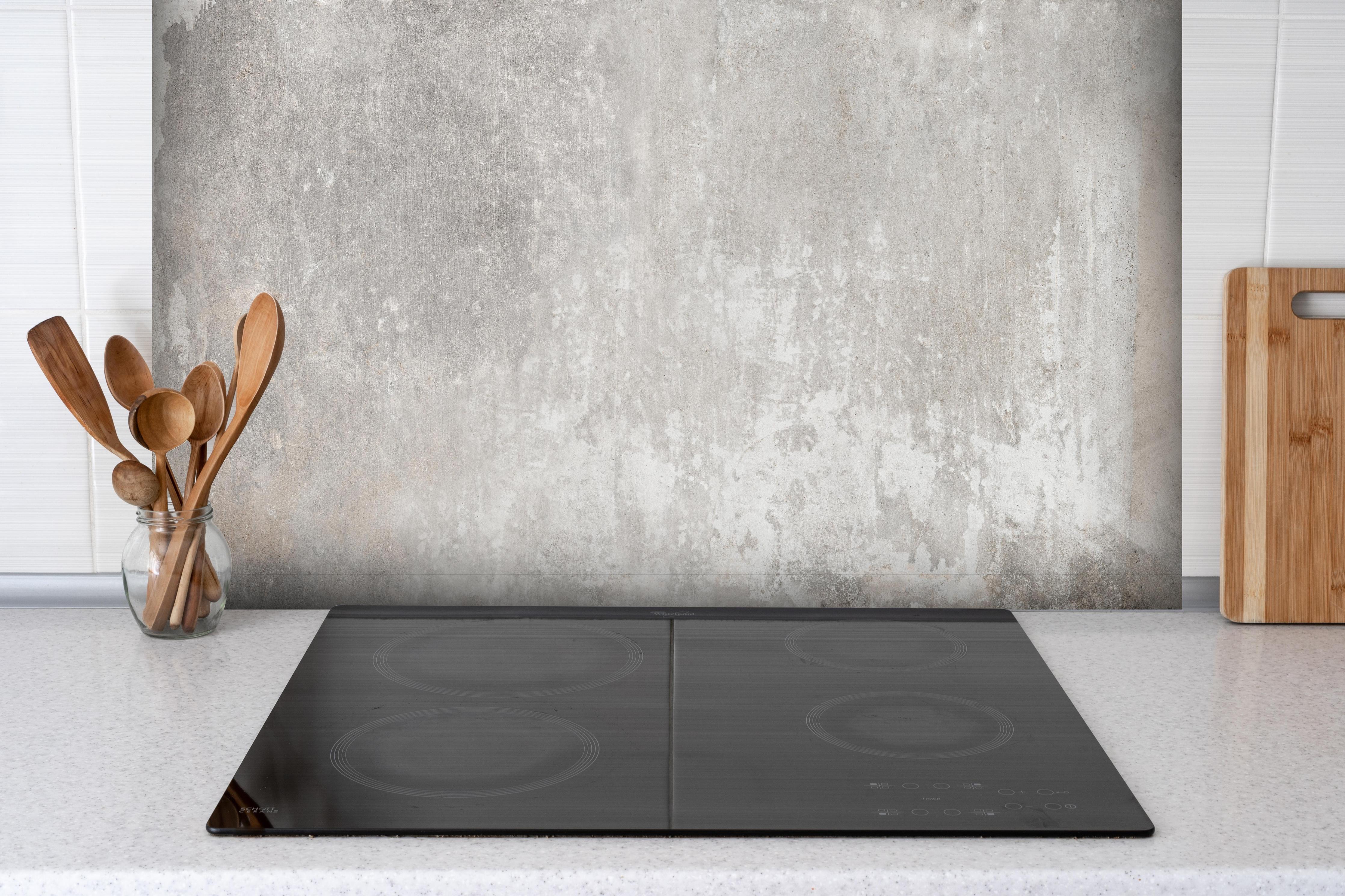 Spritzschutz - Alte Zementwandstruktur hinter einem Cerankochfeld zwischen Holz-Kochutensilien