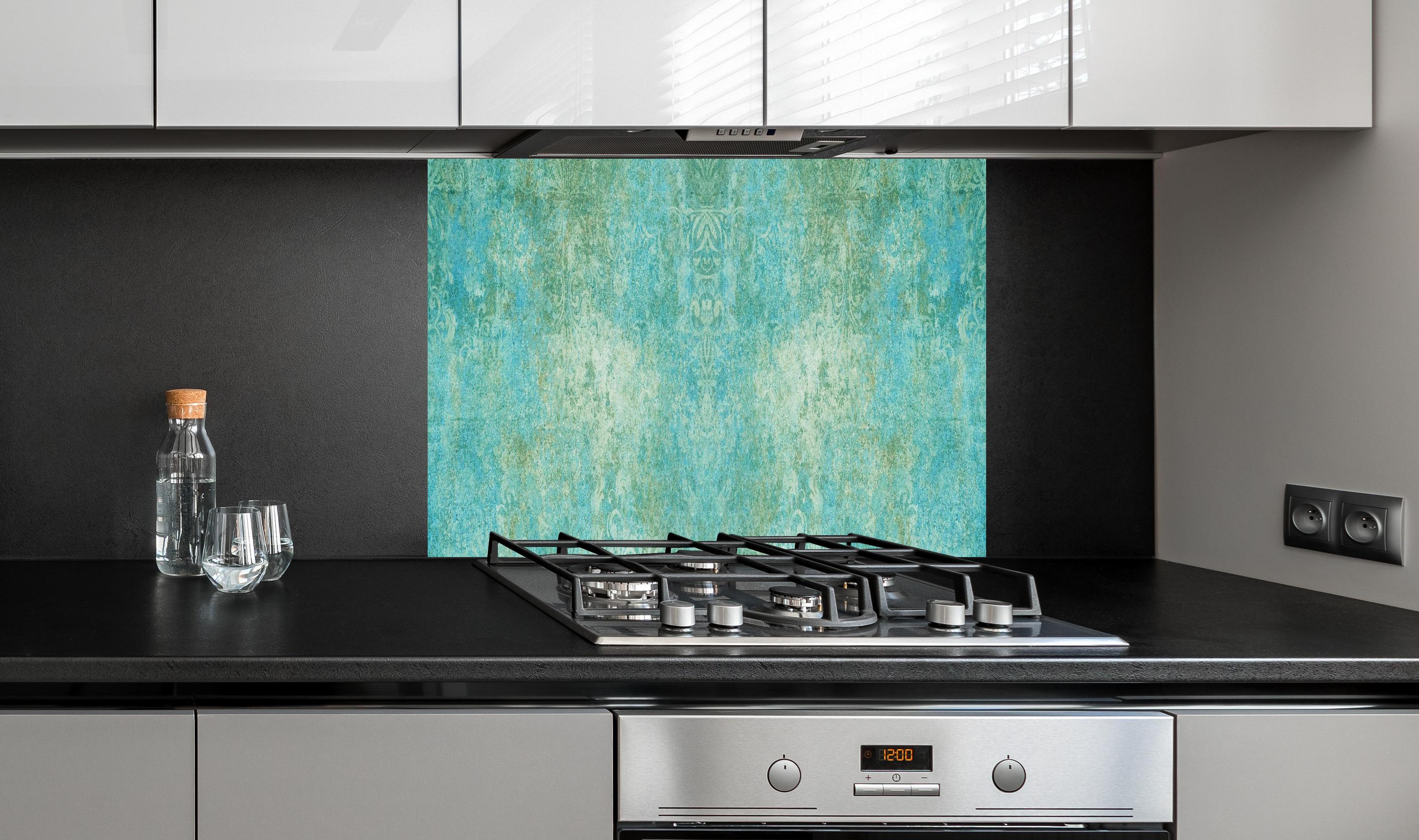 Spritzschutz - Alte blaugrüne Vintage-Fliesen hinter einem Cerankochfeld zwischen Holz-Kochutensilien