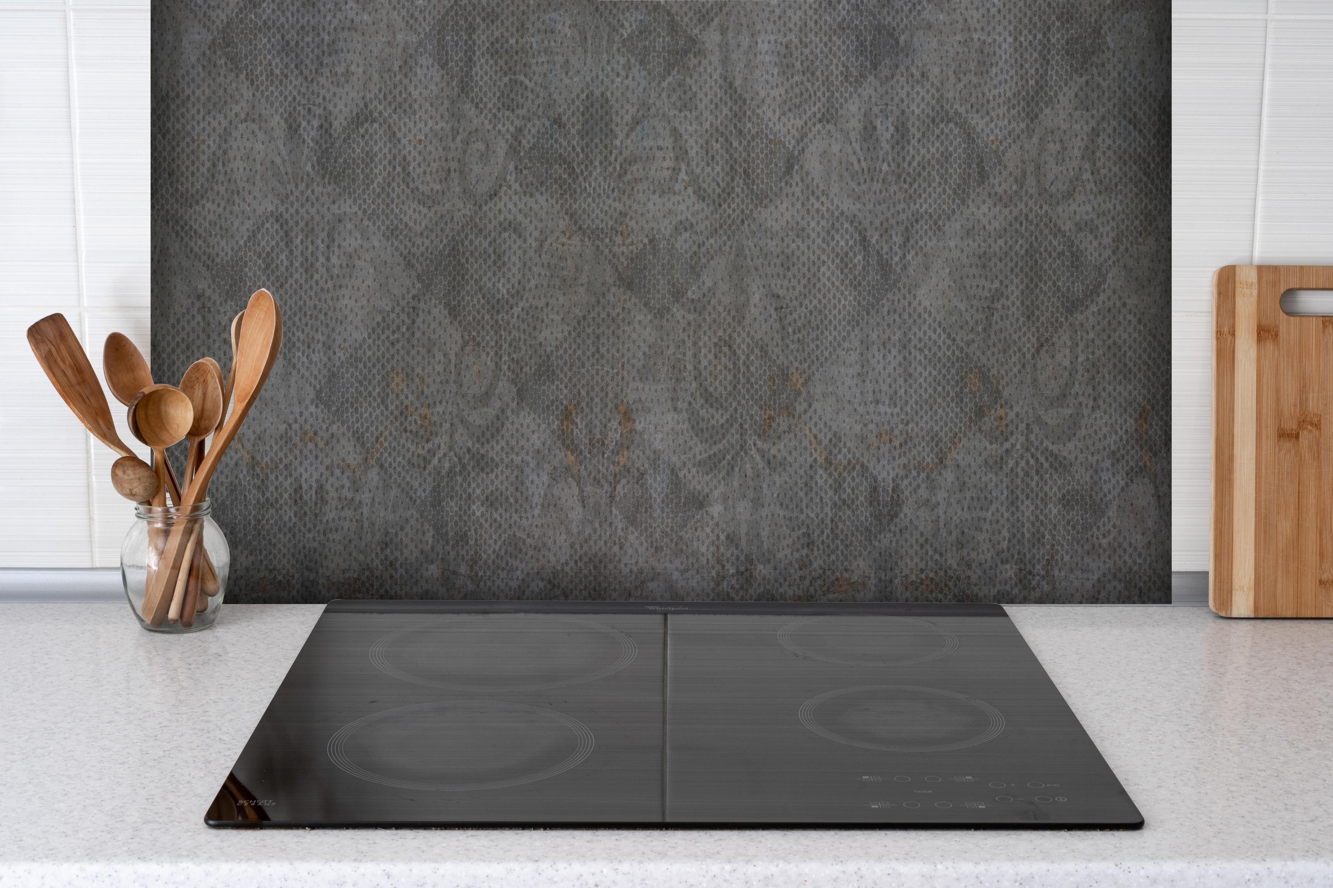Spritzschutz - Alte braunbefleckte Tapete hinter einem Cerankochfeld zwischen Holz-Kochutensilien