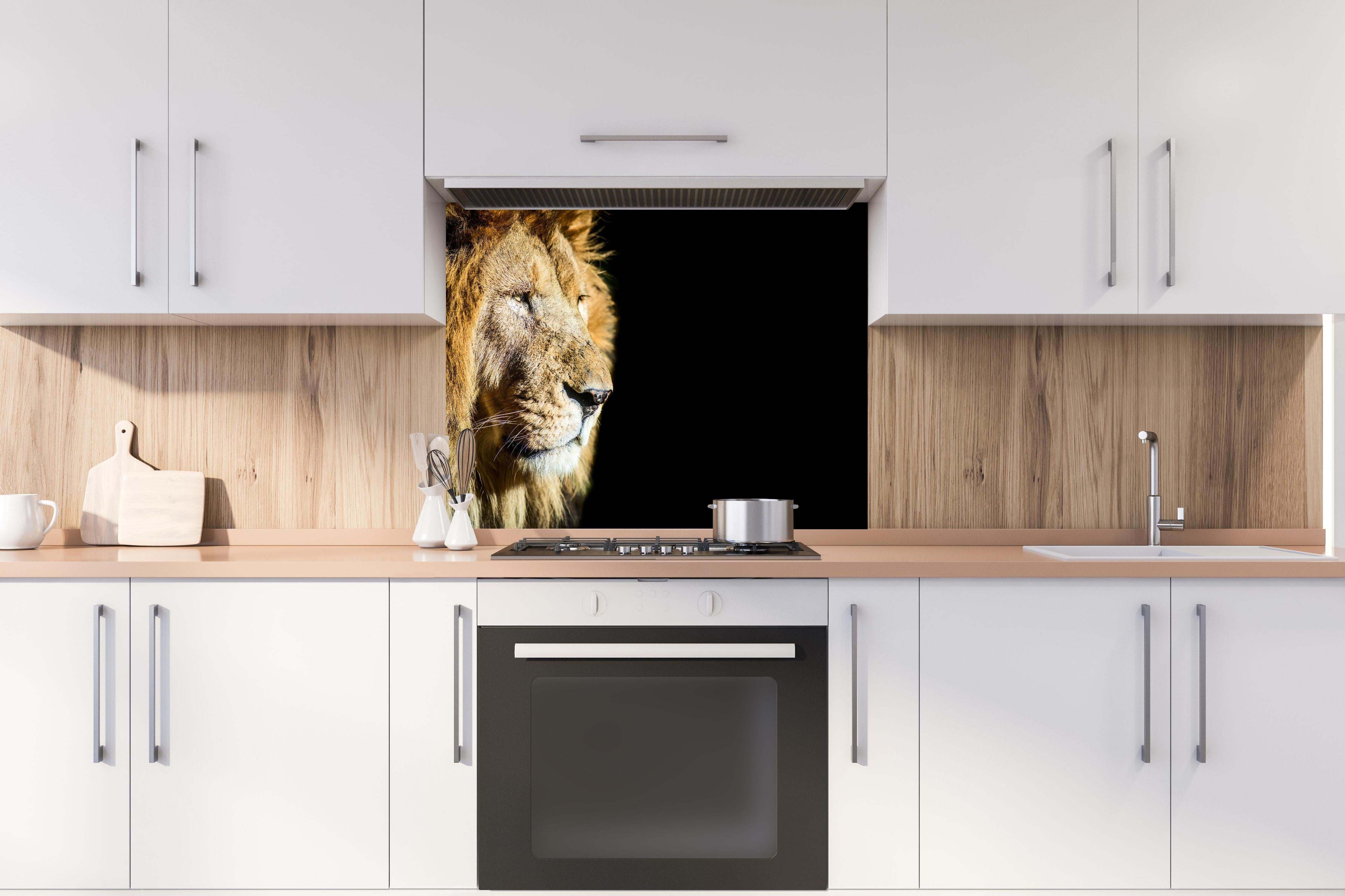 Spritzschutz - Alter Löwe auf schwarzem Hintergrund hinter einem Cerankochfeld zwischen Holz-Kochutensilien
